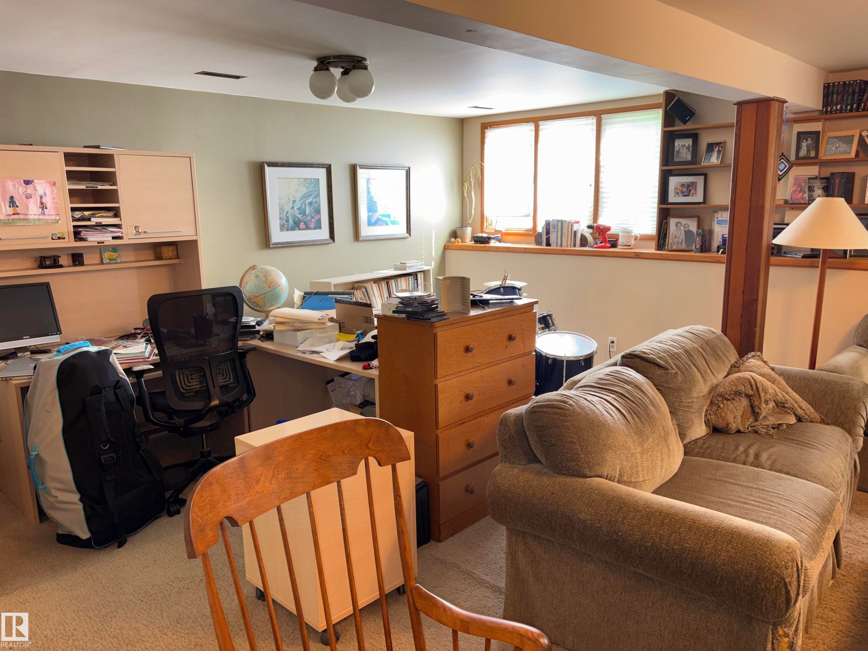 Lower-level room featuring built-in shelving, triple window with blinds, recessed wall space, and a ceiling-mounted light fixture - 8812 146 Street, Edmonton, AB