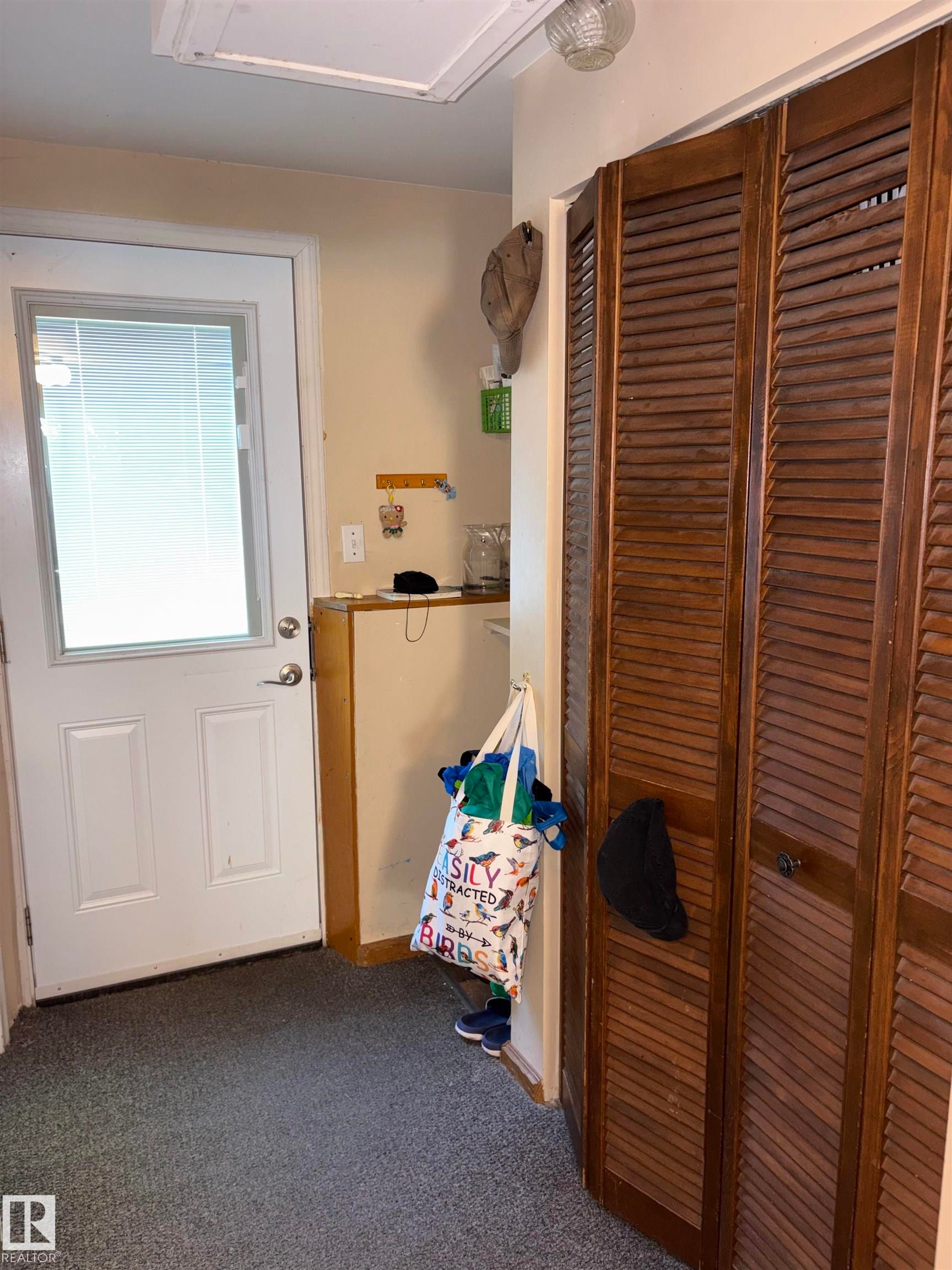 White paneled door with integrated window blinds, grey textured flooring, and louvered bifold closet doors - 8812 146 Street, Edmonton, AB