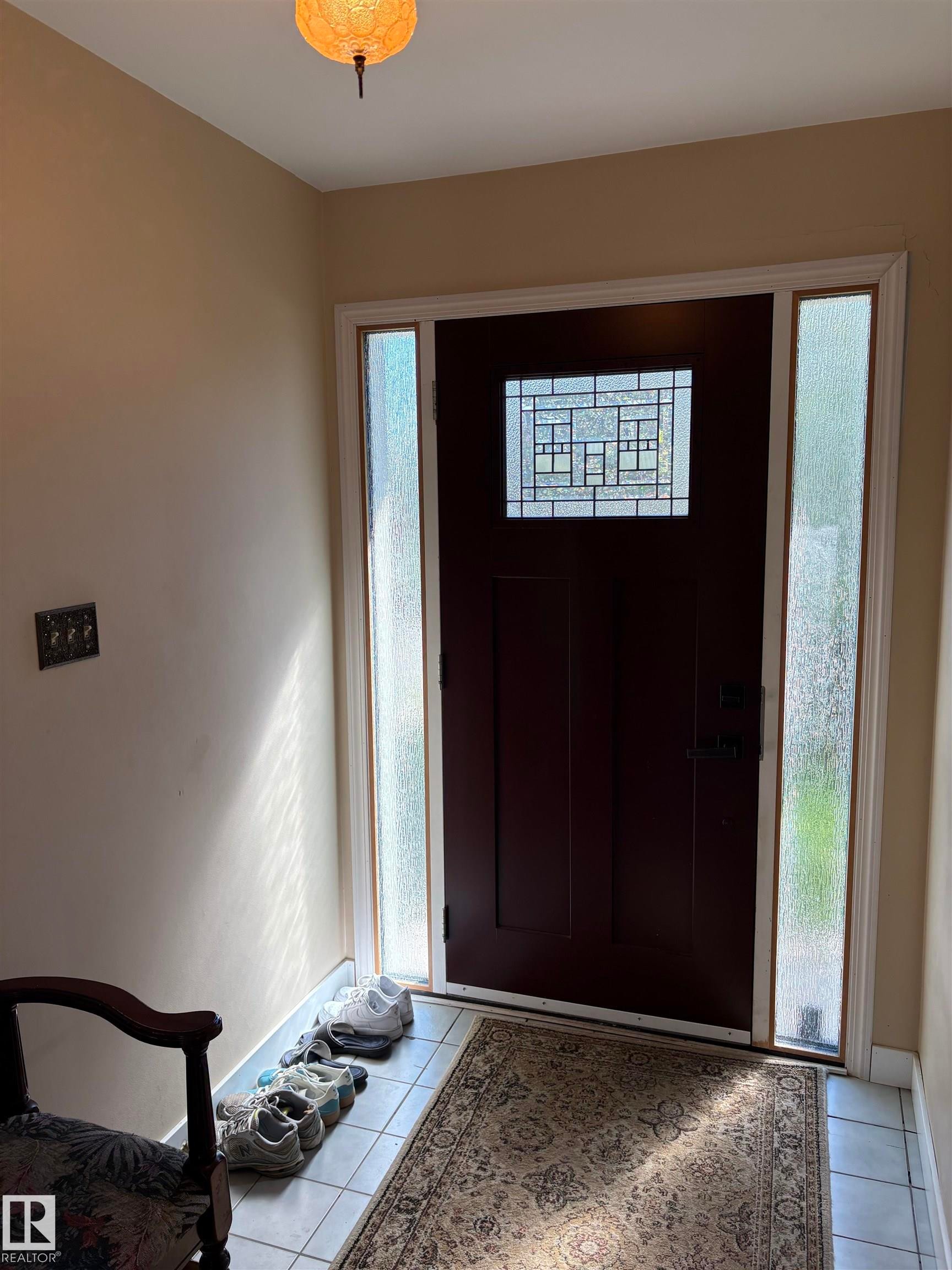 Entryway featuring a dark wood door with decorative leaded glass, framed by two frosted sidelight windows - 8812 146 Street, Edmonton, AB
