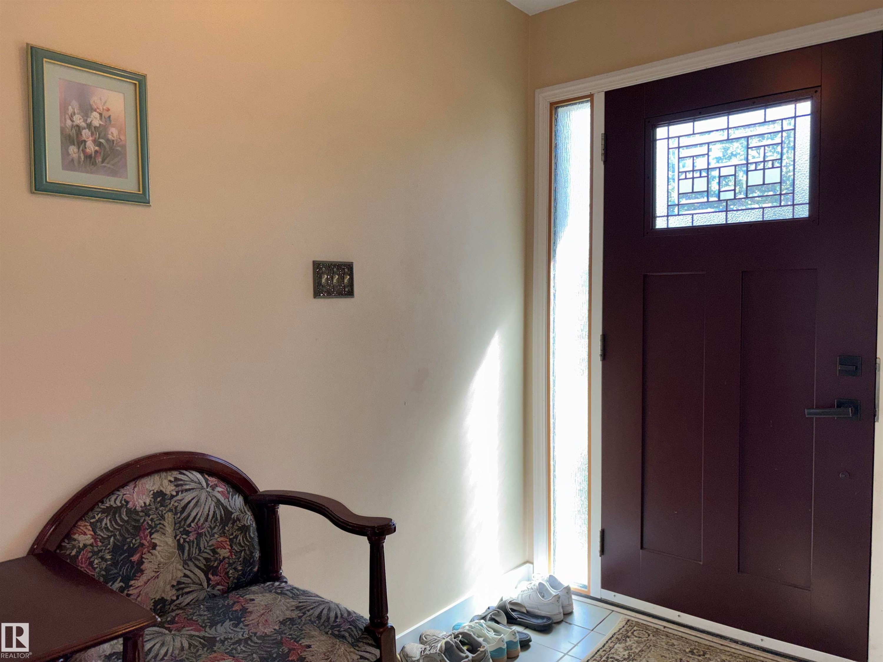 Entryway featuring a rich brown door with an intricate leaded glass insert, complemented by a frosted glass sidelight - 8812 146 Street, Edmonton, AB