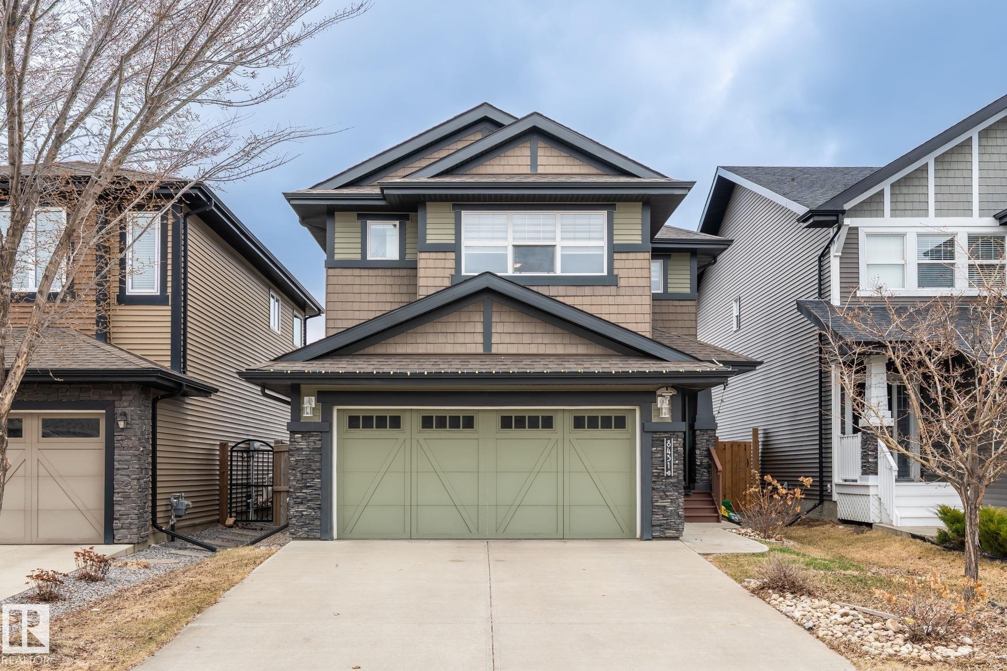 Craftsman-style exterior featuring a muted green garage door, stone pillar accents, and shake siding details - 8431 216 St Nw Nw, Edmonton, AB - Outdoor With Facade