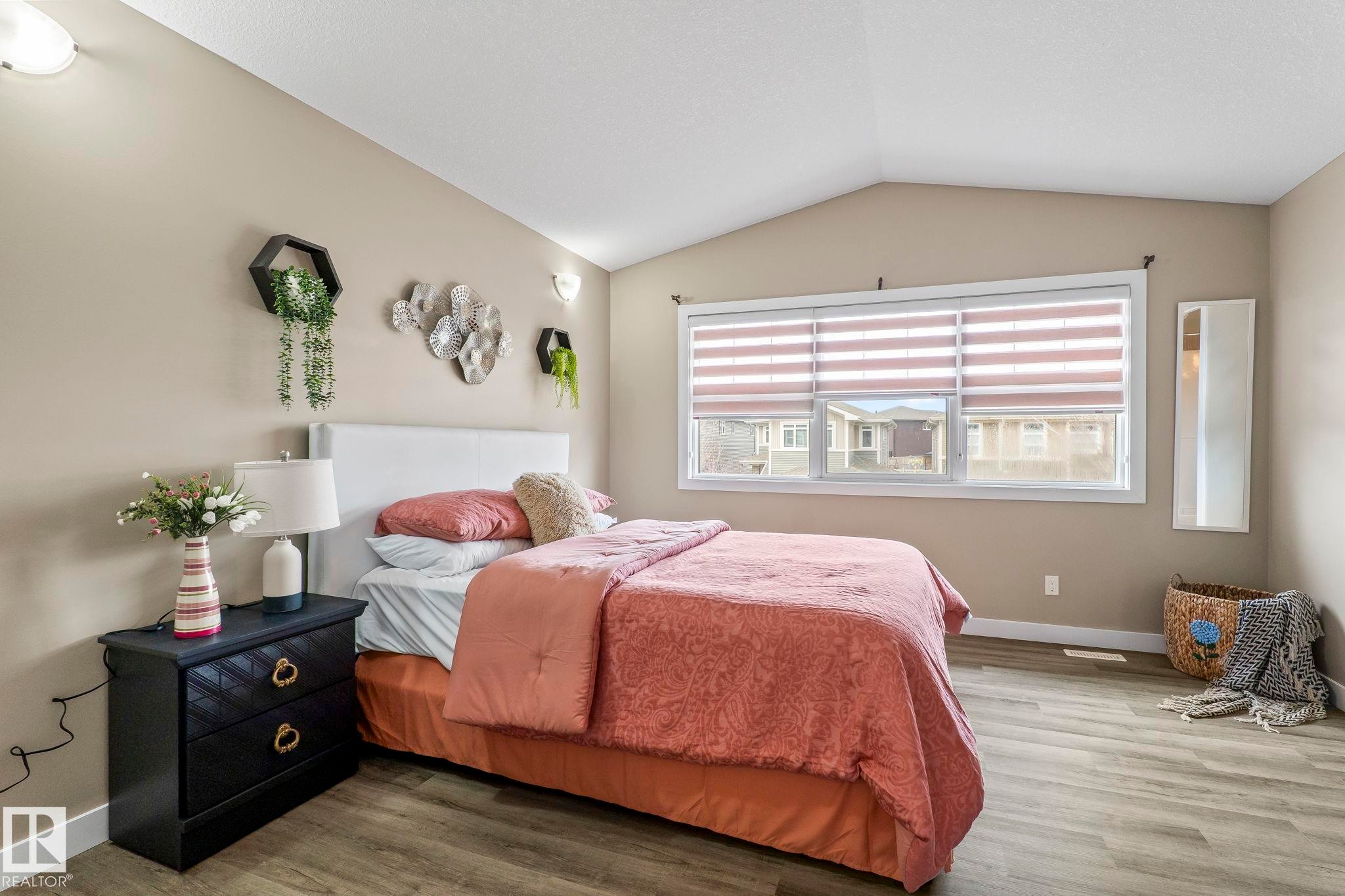 Bedroom featuring vaulted ceilings, wood-finish flooring, and a large window with horizontal blinds - 8431 216 St Nw Nw, Edmonton, AB - Indoor Photo Showing Bedroom