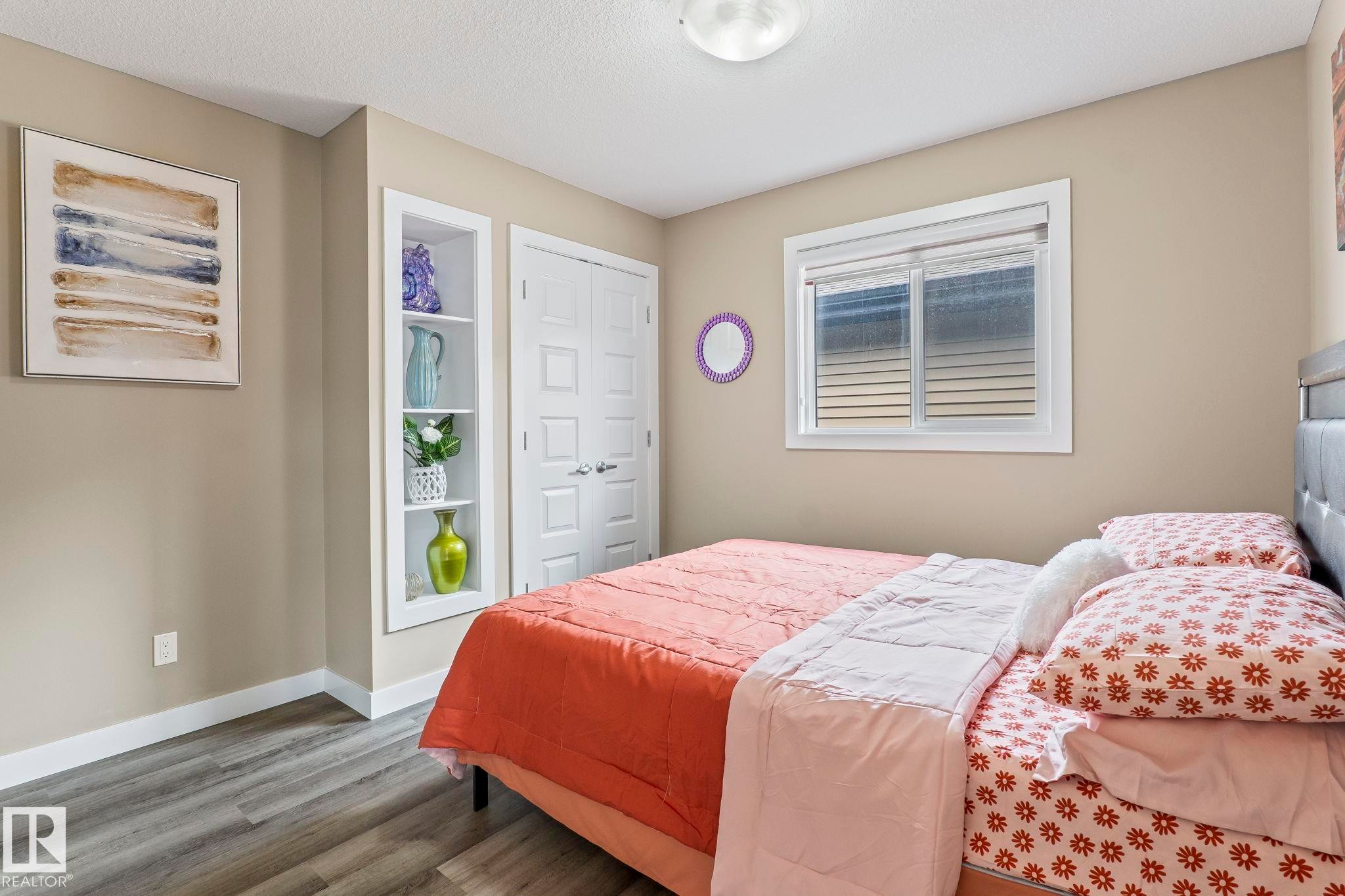 Bedroom featuring wood-finish flooring, neutral wall paint, and a built-in recessed shelving unit - 8431 216 St Nw Nw, Edmonton, AB - Indoor Photo Showing Bedroom