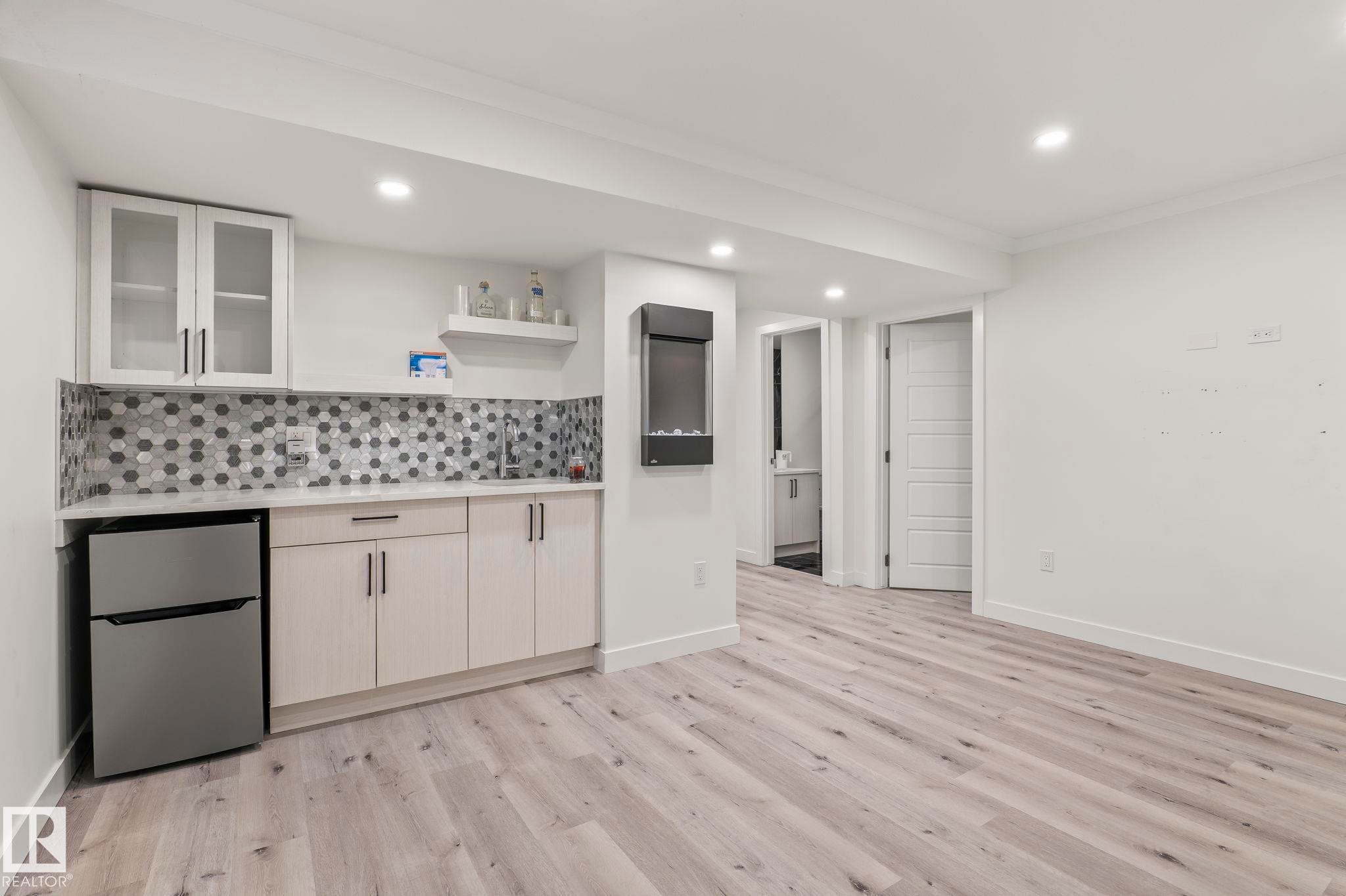 Wet bar featuring white cabinetry, hexagonal tile backsplash, and a compact refrigerator - 8431 216 St Nw Nw, Edmonton, AB - Indoor