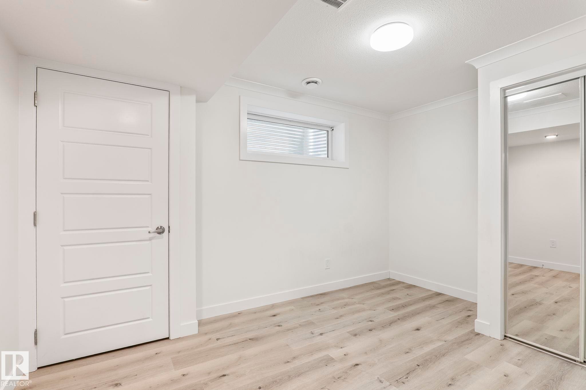 Spacious room featuring wood-finish flooring, white walls, and crown molding - 8431 216 St Nw Nw, Edmonton, AB - Indoor Photo Showing Other Room