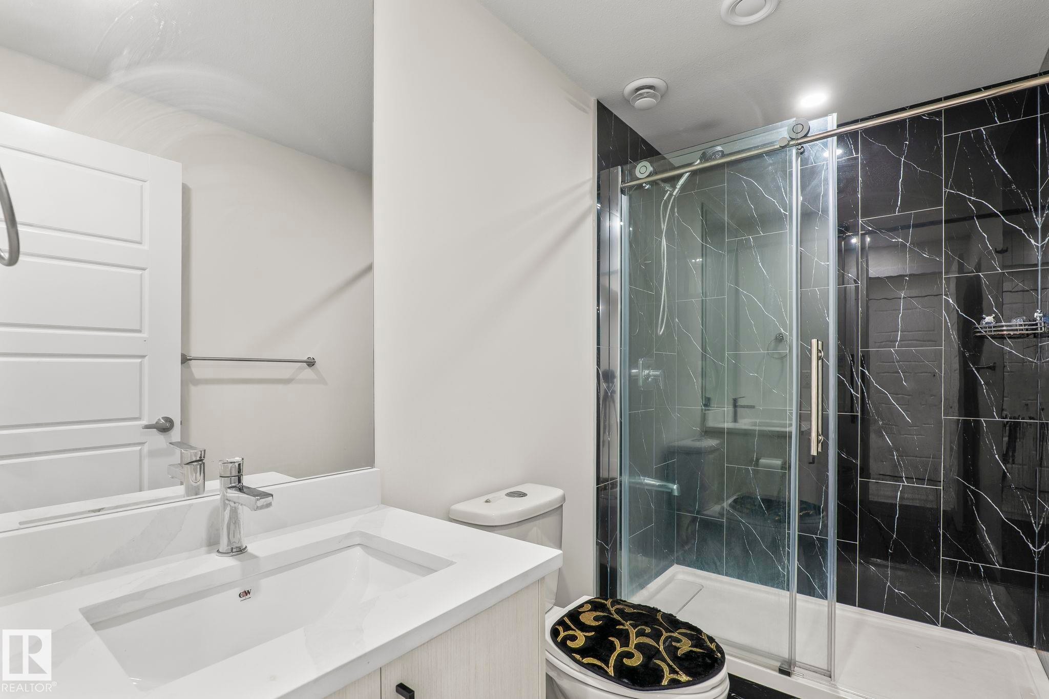 Modern bathroom featuring a single vanity with an integrated sink, polished chrome faucet, and light wood-finish cabinetry - 8431 216 St Nw Nw, Edmonton, AB - Indoor Photo Showing Bathroom