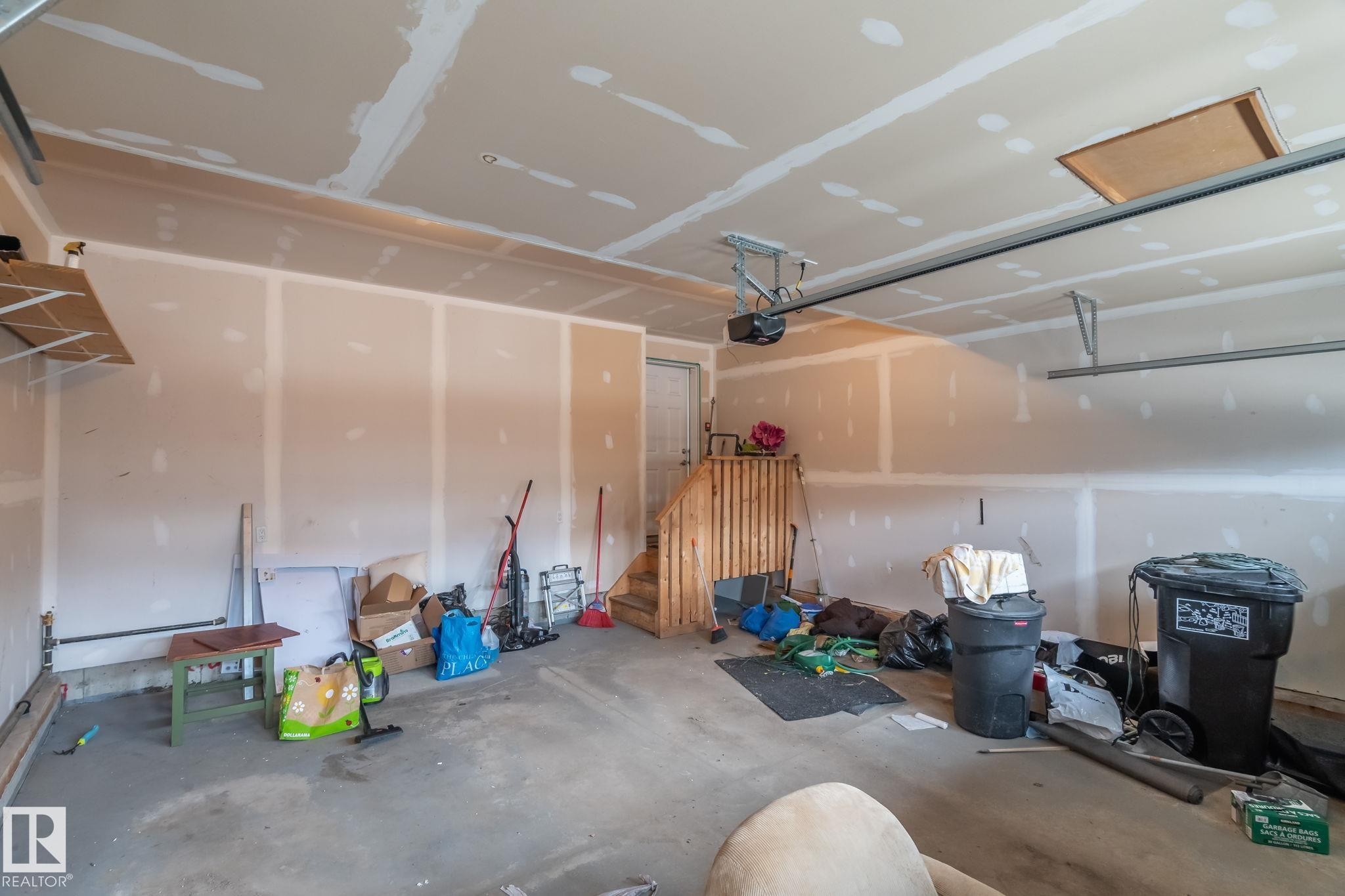 Unfinished garage space featuring a concrete floor, exposed drywall, and an automatic garage door opener - 8431 216 St Nw Nw, Edmonton, AB - Indoor Photo Showing Garage
