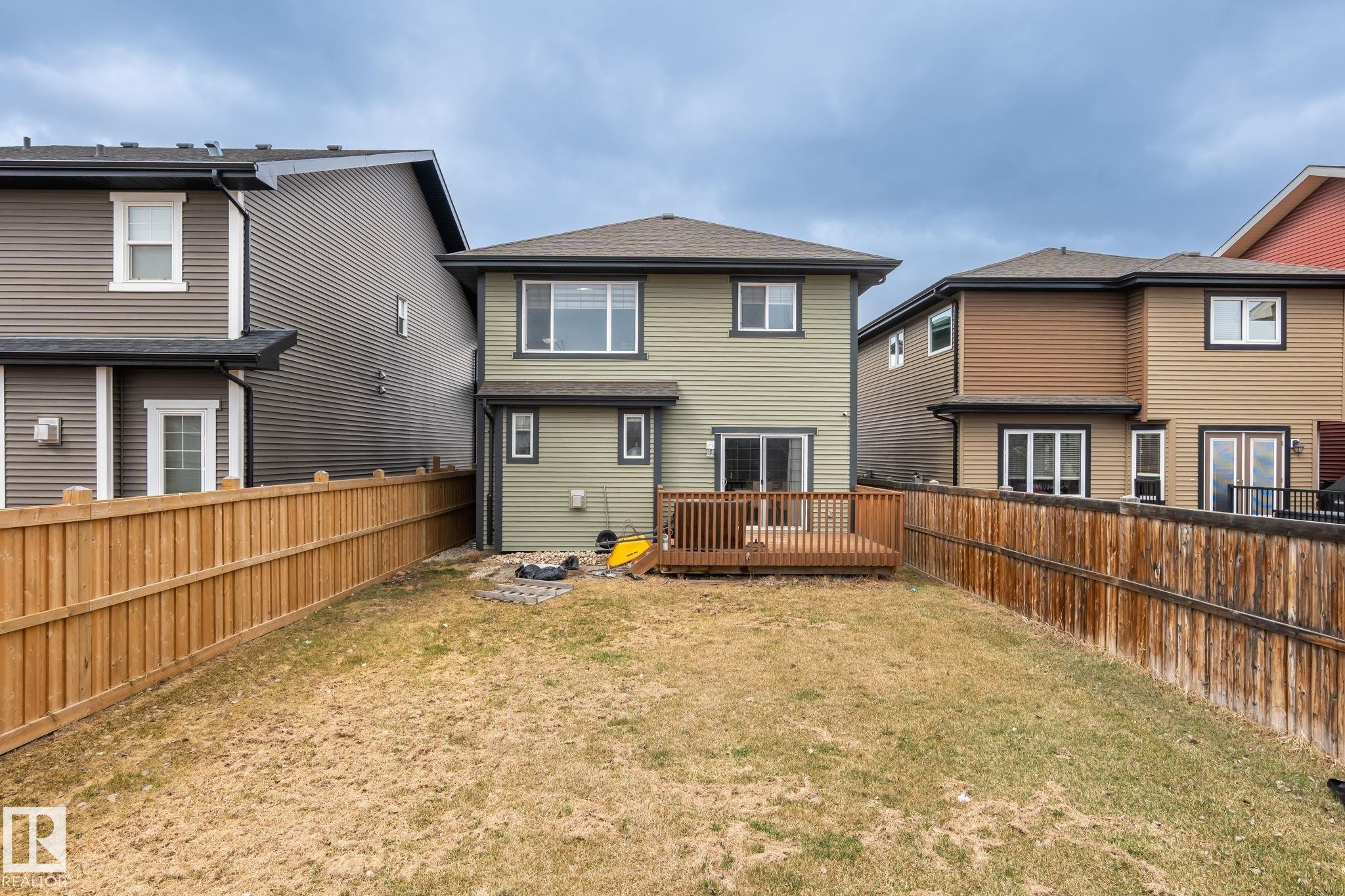 Expansive backyard featuring a wooden deck, sliding patio door access, and full perimeter fencing - 8431 216 St Nw Nw, Edmonton, AB - Outdoor With Exterior