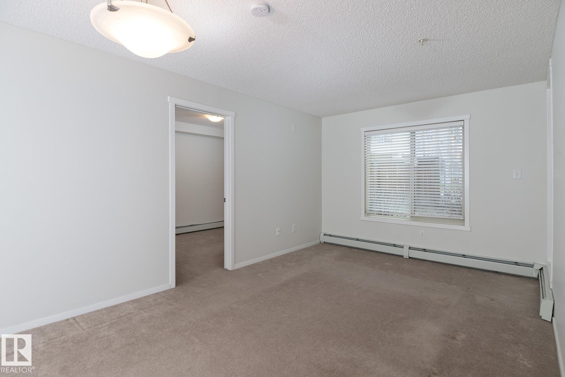Neutral-toned carpeting extends throughout this room, complemented by a window with horizontal blinds - 111 25 Element Dr, St. Albert, AB - Indoor Photo Showing Other Room