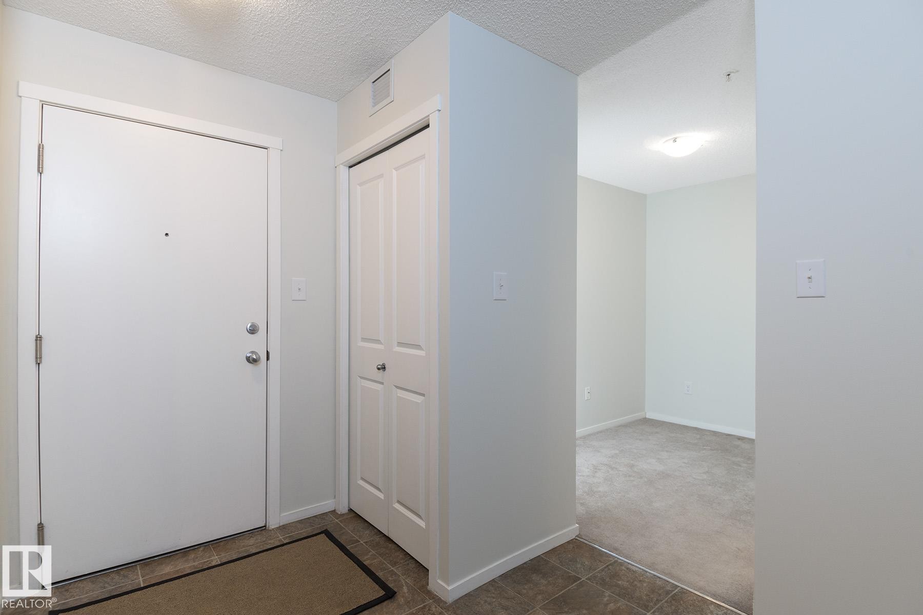 Entry foyer featuring a white entrance door with brushed nickel hardware, bifold closet doors, and tile flooring - 111 25 Element Dr, St. Albert, AB - Indoor Photo Showing Other Room