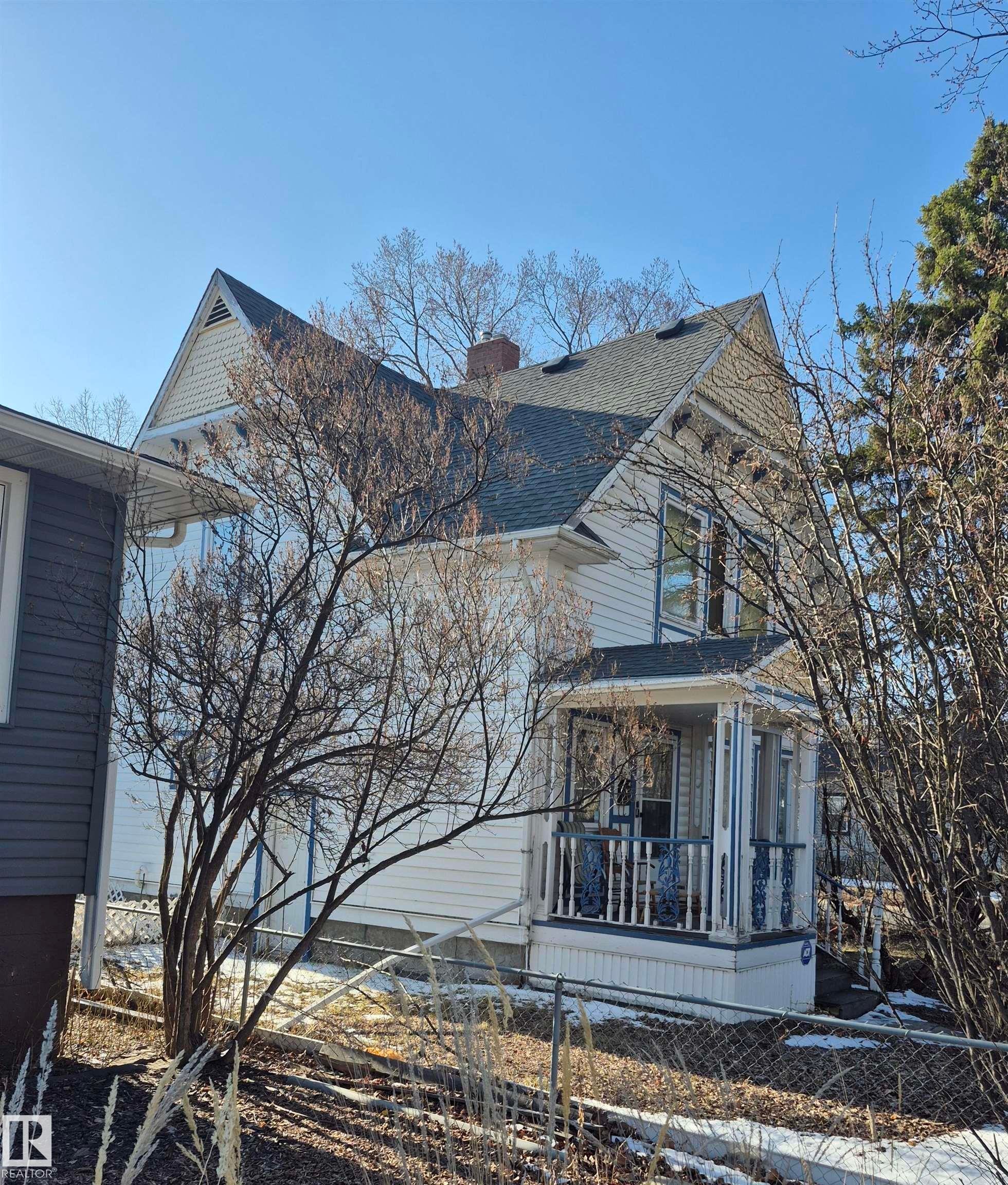 White two-story residence featuring a covered front porch (3.12x2.26) with decorative railings - 11301 87 Street, Edmonton, AB - Outdoor