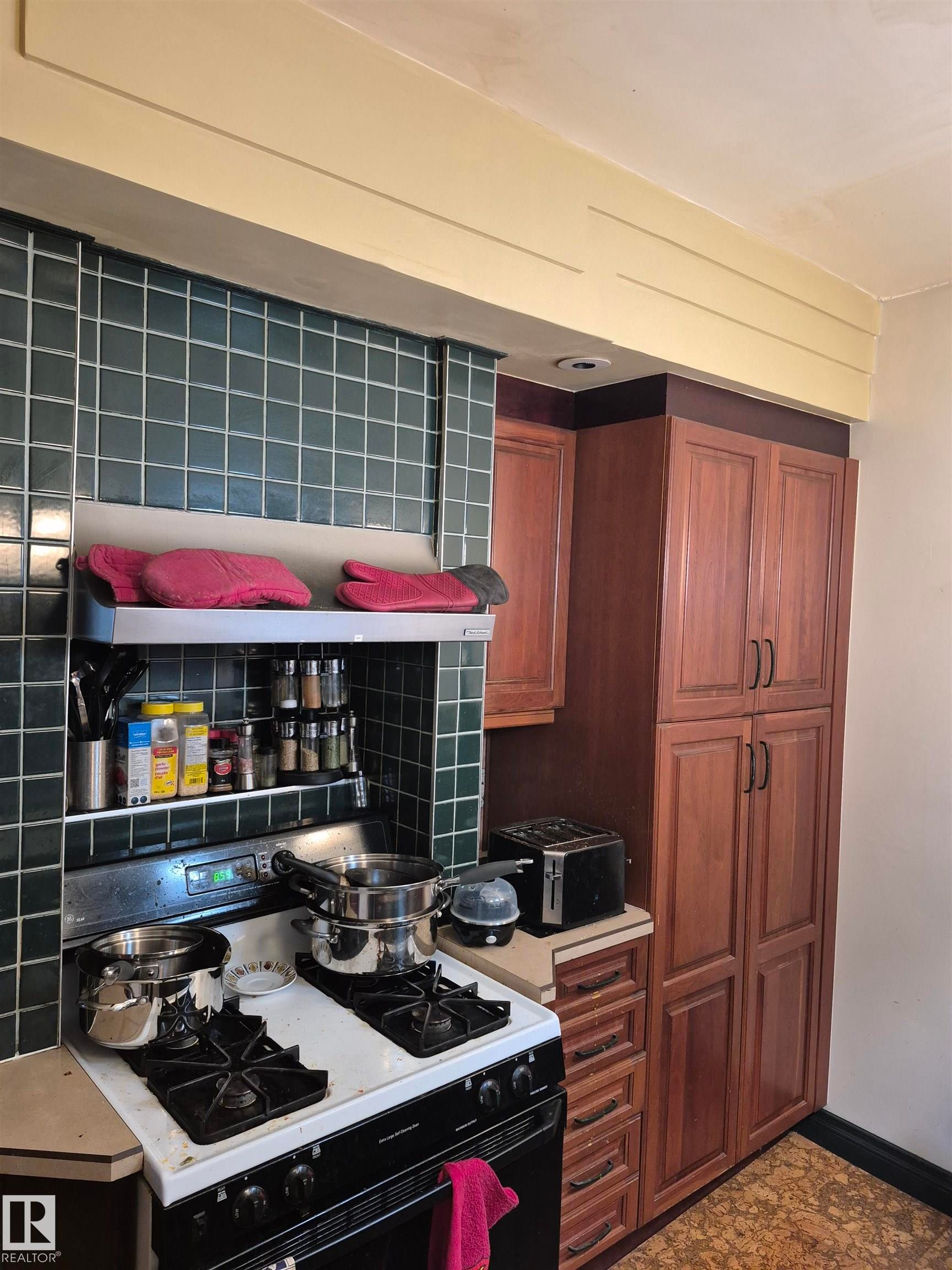 Kitchen featuring a dark green tiled backsplash, cherry wood cabinetry, a freestanding gas range, and neutral countertops - 11301 87 Street, Edmonton, AB - Indoor Photo Showing Kitchen