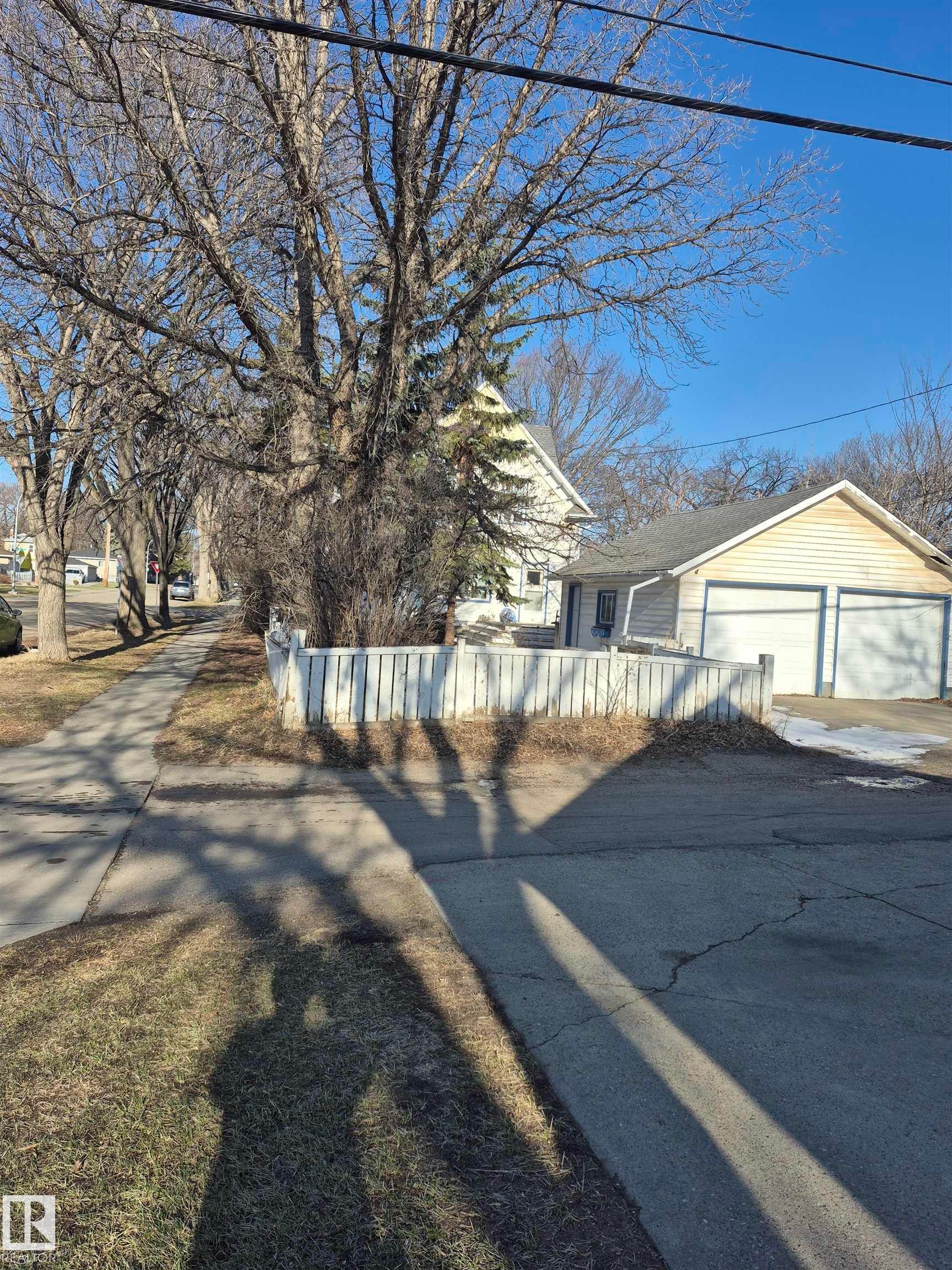 Two-car garage with white paneled doors and blue trim, visible from a paved driveway - 11301 87 Street, Edmonton, AB - Outdoor