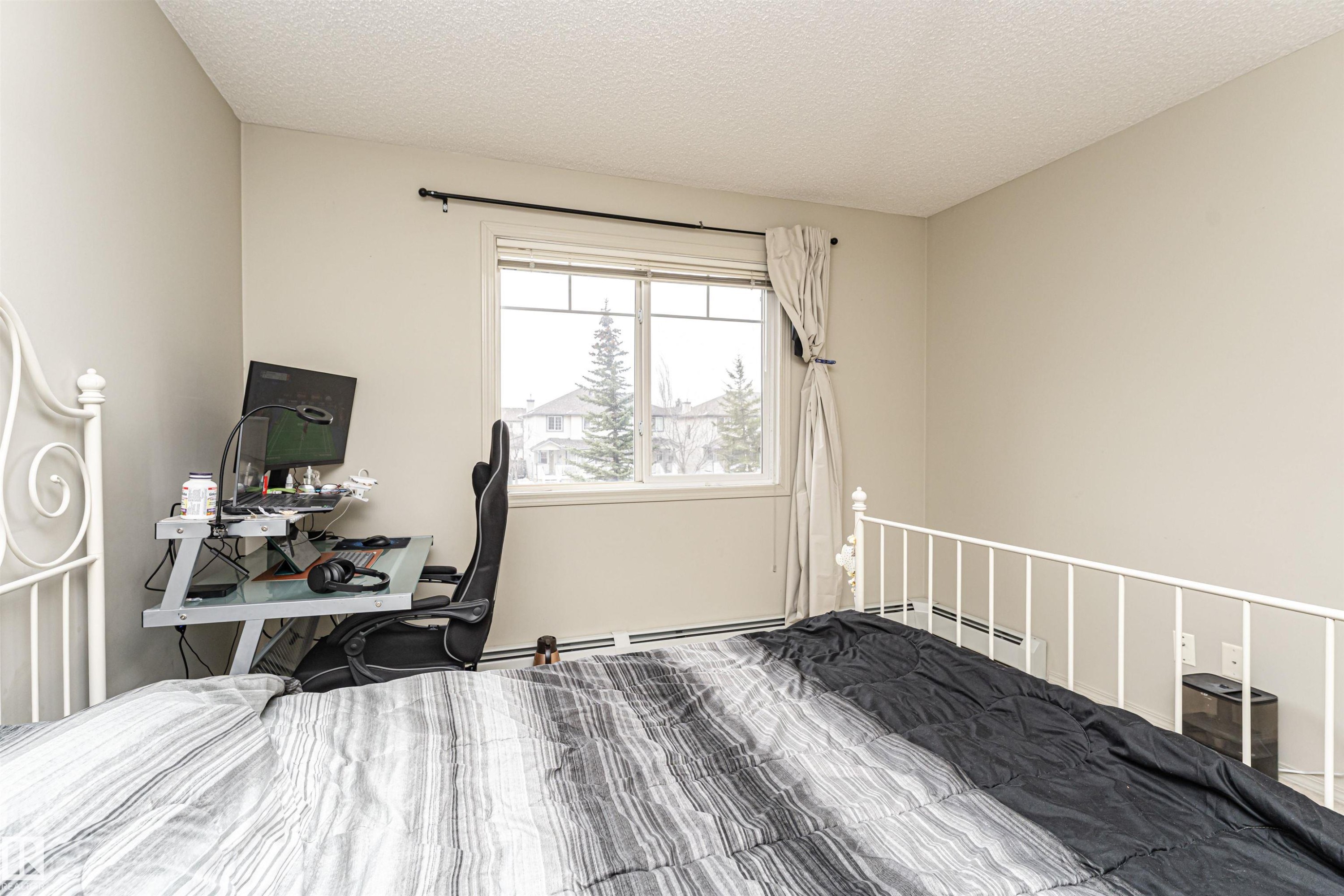 Spacious room featuring neutral painted walls and a textured ceiling - 219 646 Mcallister Loop, Edmonton, AB - Indoor