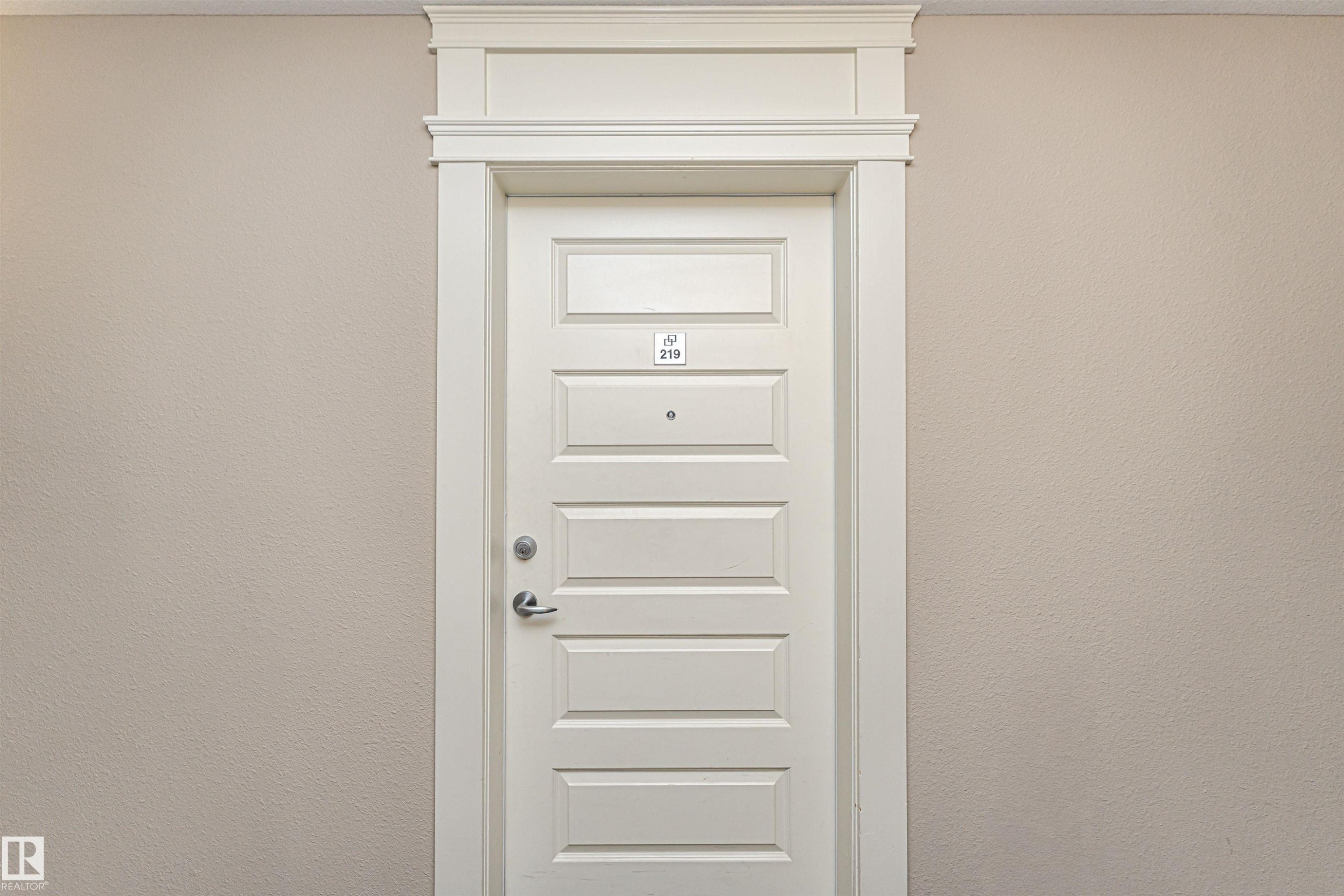 Crisp white six-panel door with decorative trim and brushed nickel hardware - 219 646 Mcallister Loop, Edmonton, AB - Photo Showing Other Room