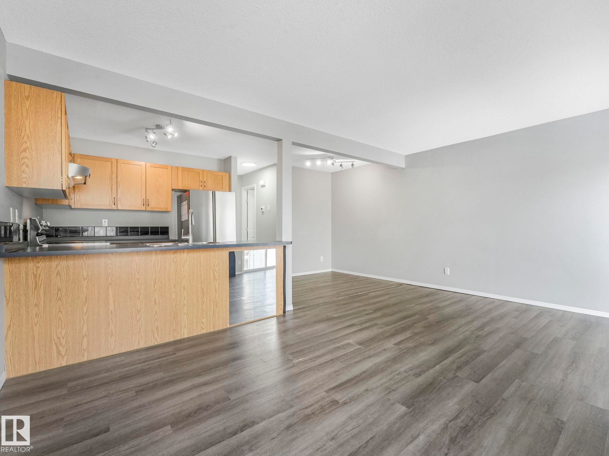 Open concept living area featuring wood-look flooring and light grey walls - 175 150 Edwards Drive, Edmonton, AB - Indoor Photo Showing Kitchen