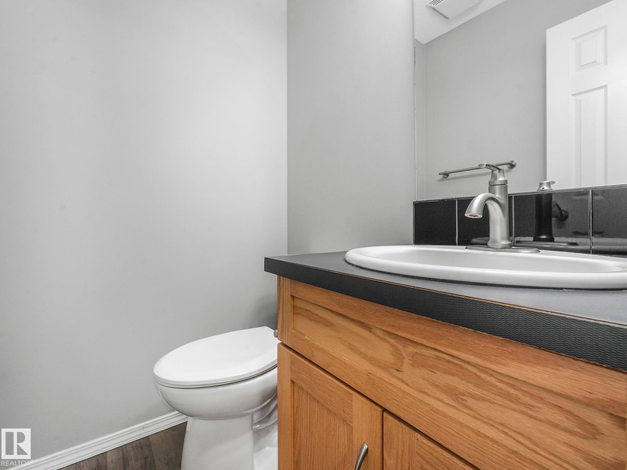 This property features a bathroom with a light wood vanity, a black countertop, and a white sink with a brushed nickel faucet - 175 150 Edwards Drive, Edmonton, AB - Indoor Photo Showing Bathroom