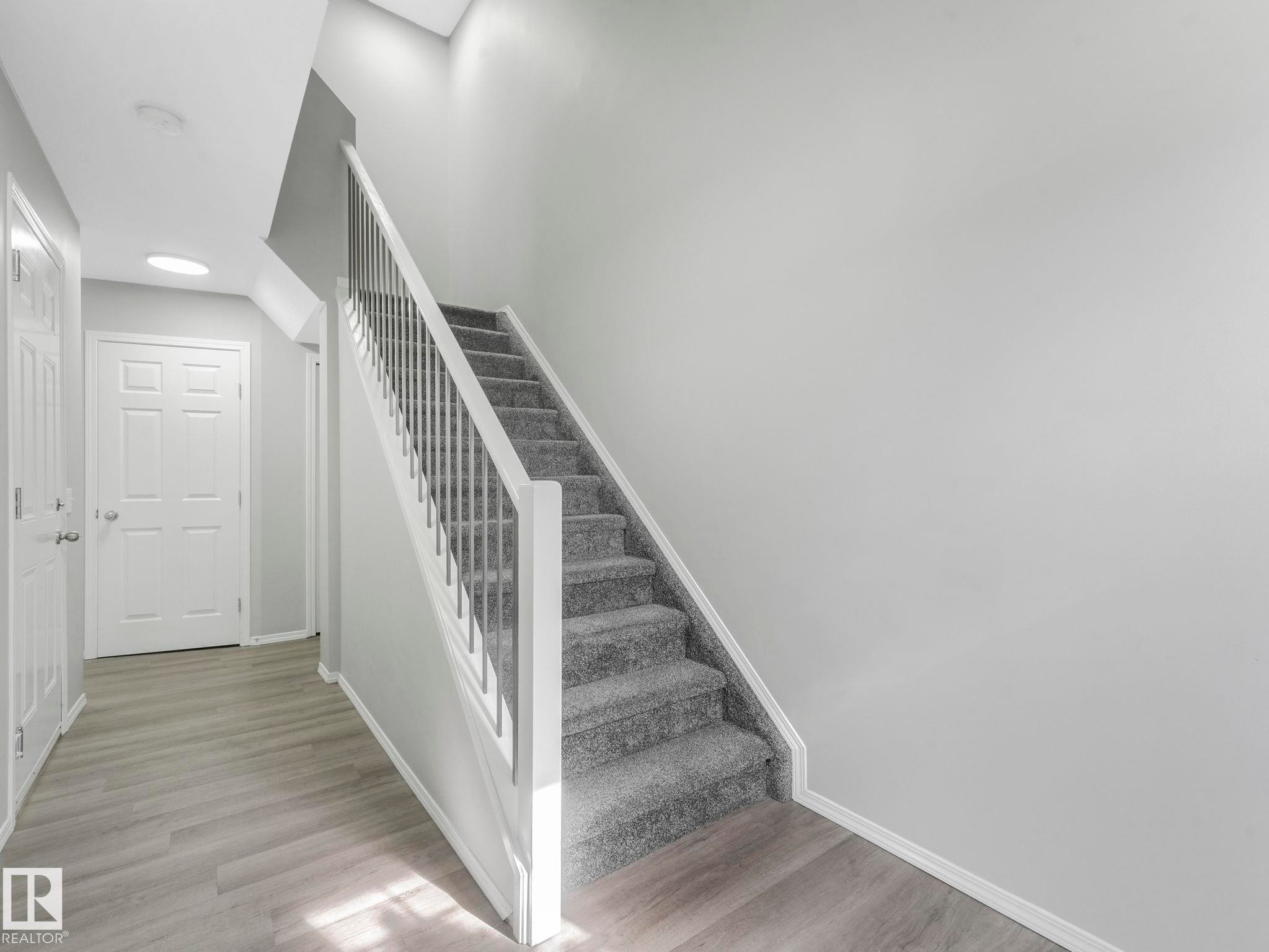 The entry hall features light-colored flooring, a staircase with carpeting, and a white paneled door - 175 150 Edwards Drive, Edmonton, AB - Indoor Photo Showing Other Room
