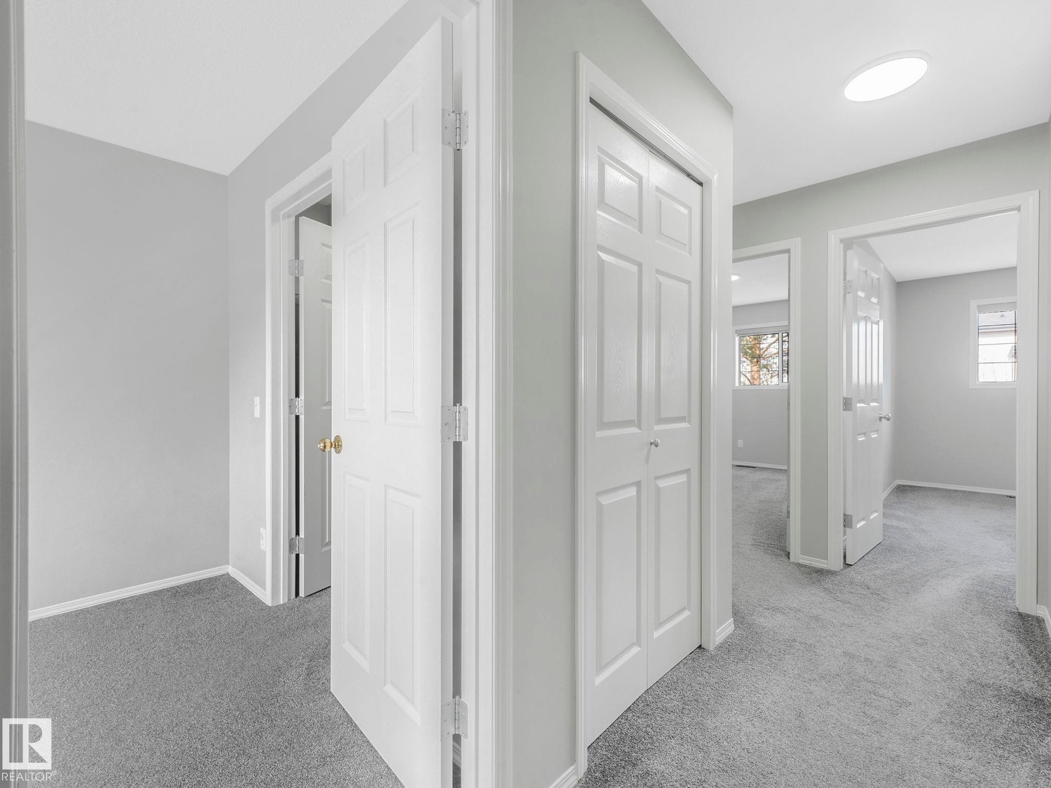 The hallway features light gray walls and gray carpeting, with white doors and trim - 175 150 Edwards Drive, Edmonton, AB - Indoor Photo Showing Other Room