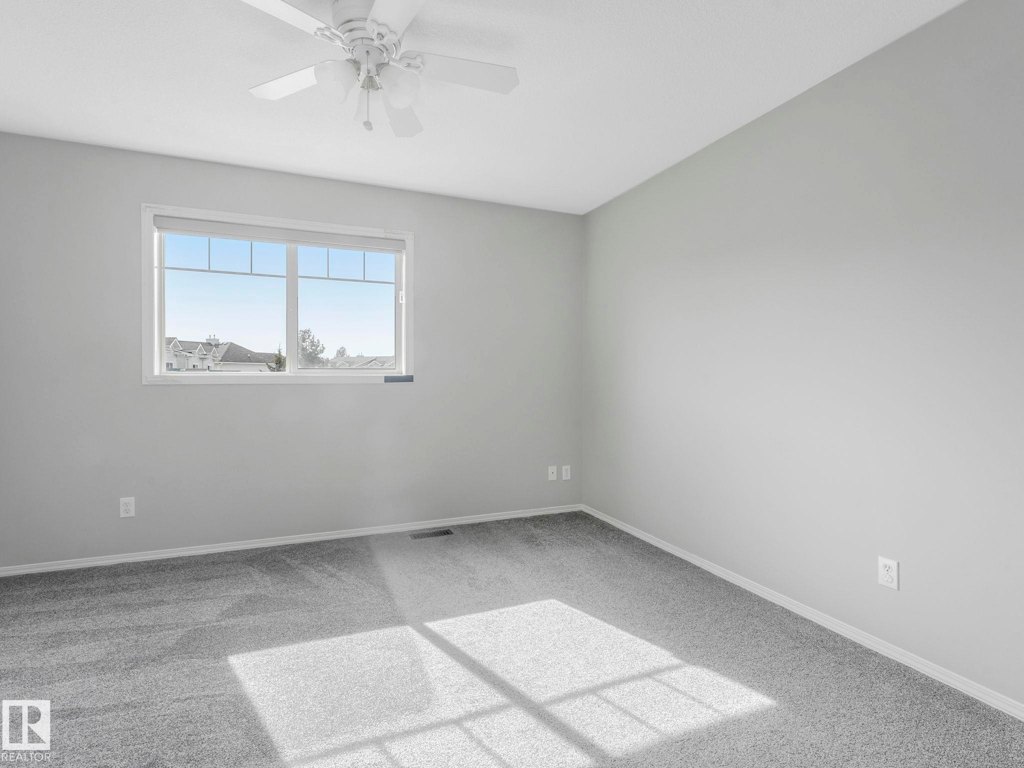 This room features light grey walls, grey carpeting, and a window providing natural light - 175 150 Edwards Drive, Edmonton, AB - Indoor Photo Showing Other Room