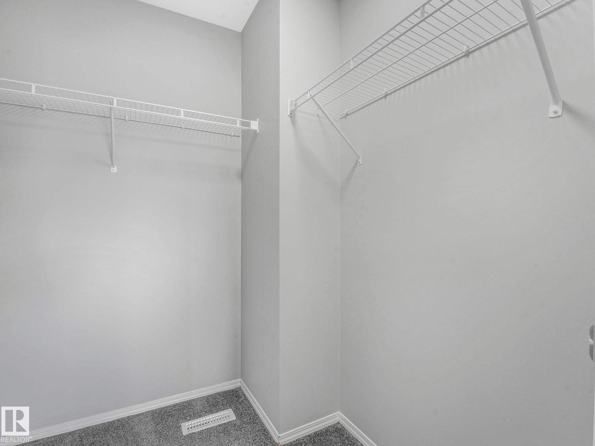 The property includes a closet with light grey walls, carpeted flooring, and white wire shelving - 175 150 Edwards Drive, Edmonton, AB - Indoor With Storage