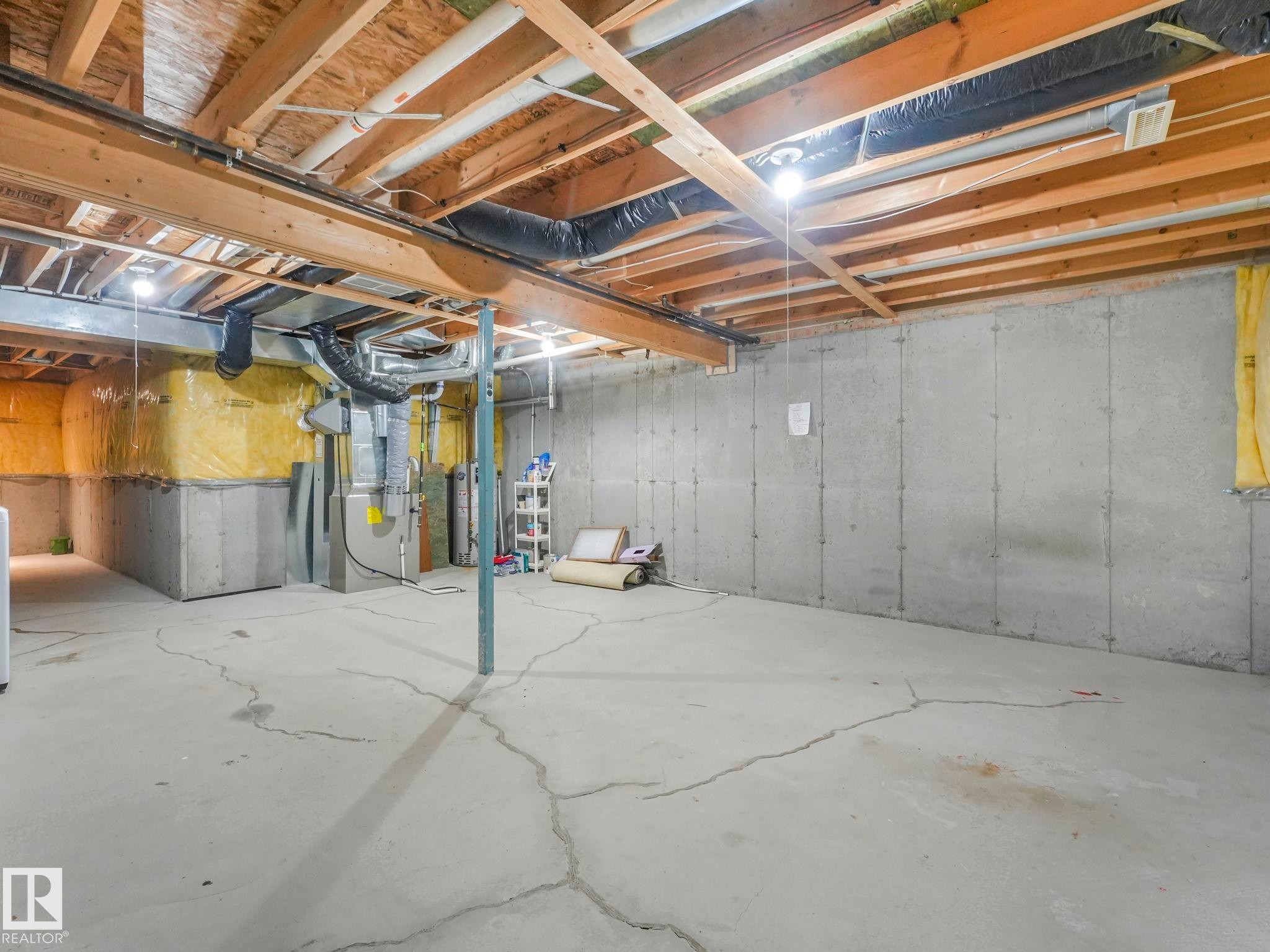 The unfinished basement features concrete walls, exposed wooden ceiling joists, and a concrete floor - 175 150 Edwards Drive, Edmonton, AB - Indoor Photo Showing Basement