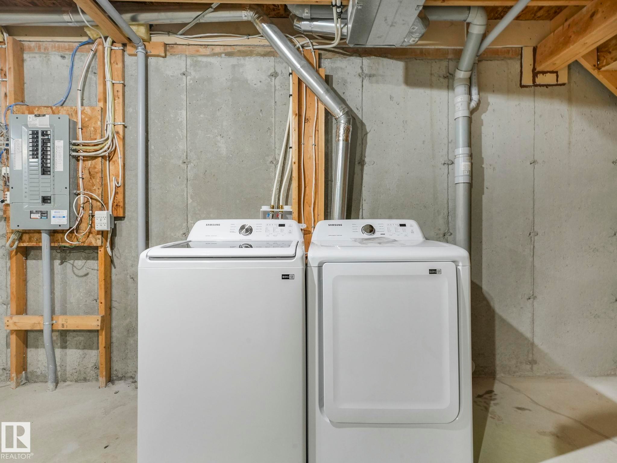 The utility area features a washing machine, a dryer, and a circuit breaker panel - 175 150 Edwards Drive, Edmonton, AB - Indoor Photo Showing Laundry Room