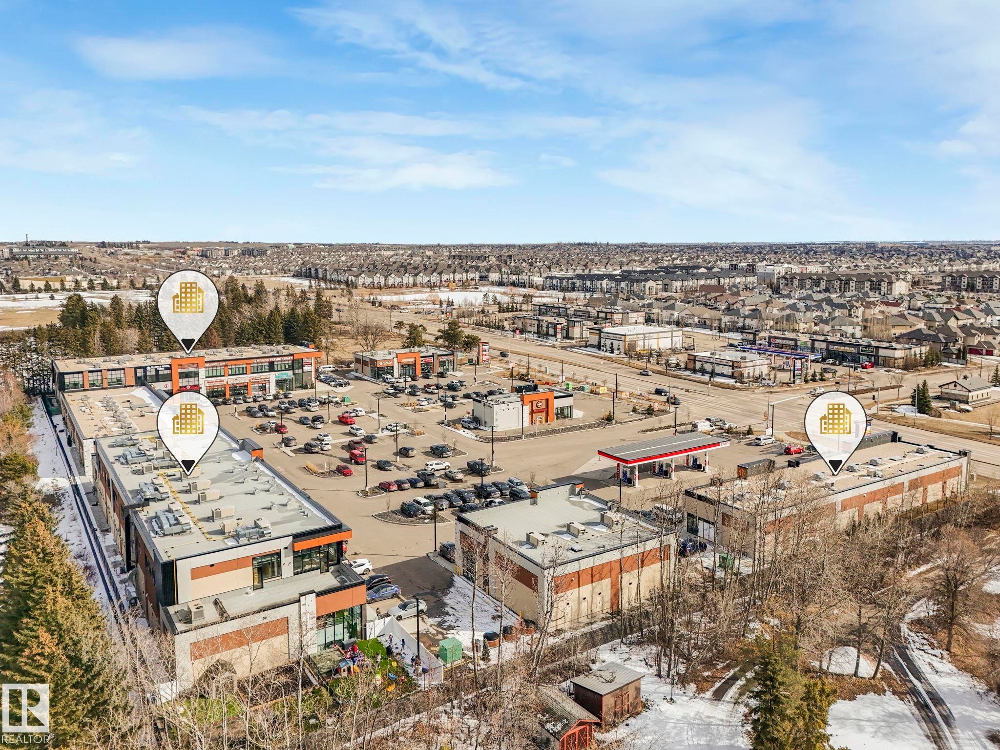 Aerial view of a commercial property featuring a parking lot, multiple buildings, and a gas station - 175 150 Edwards Drive, Edmonton, AB - Outdoor With View