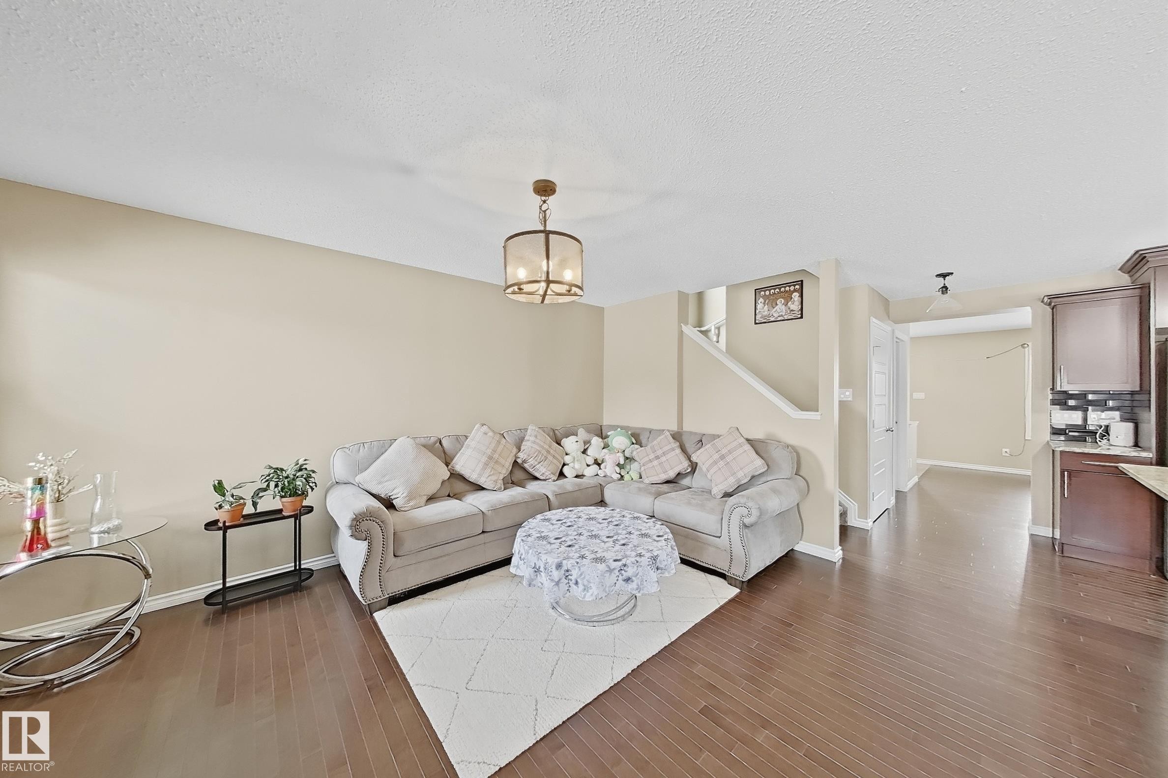 Spacious living area featuring wood-finish flooring, neutral wall tones, and a contemporary ceiling fixture - 3609 Weidle Bend, Edmonton, AB - Indoor Photo Showing Living Room