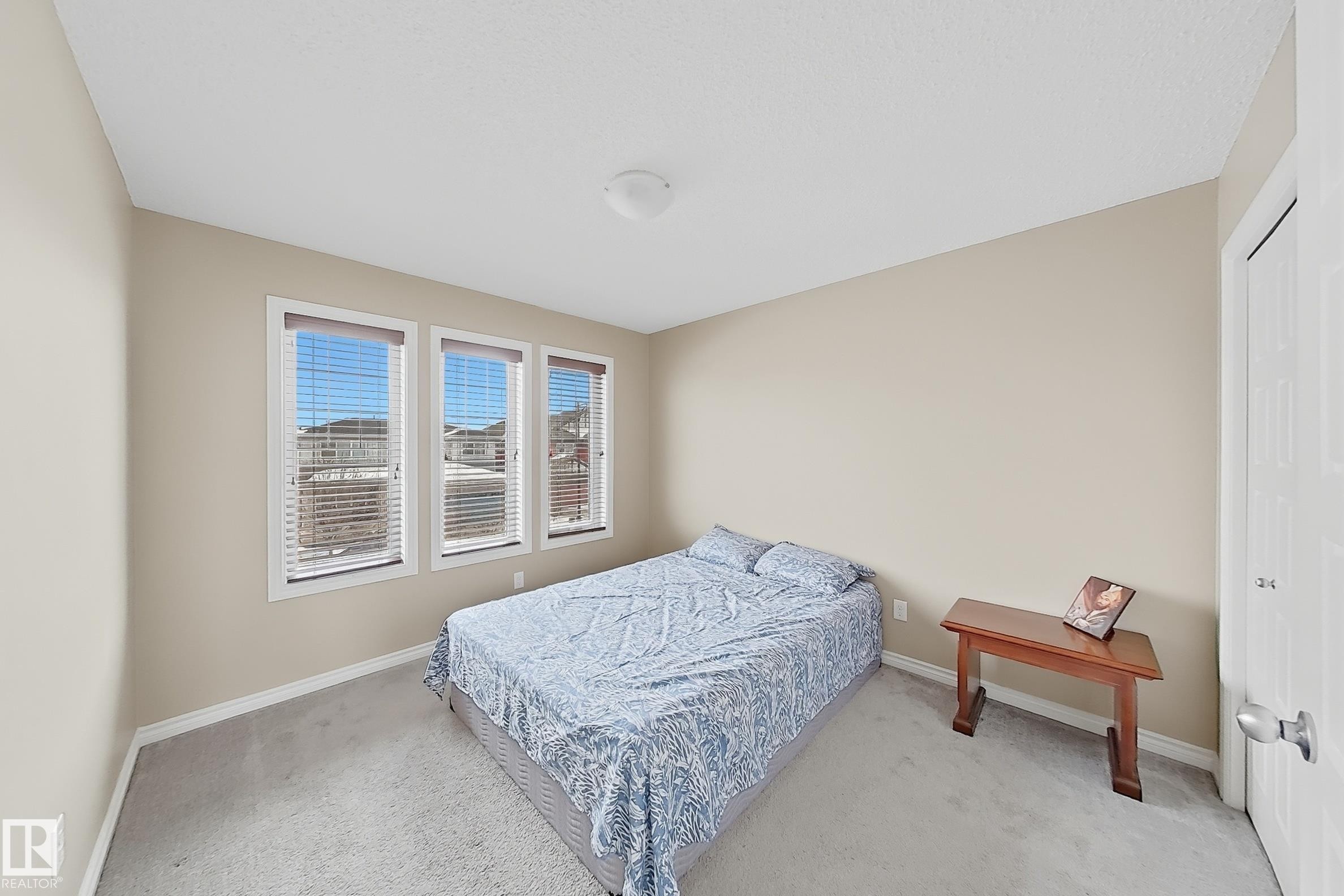 Room featuring three white-framed windows with blinds, light tan wall paint, and gray carpeting - 3609 Weidle Bend, Edmonton, AB - Indoor Photo Showing Bedroom