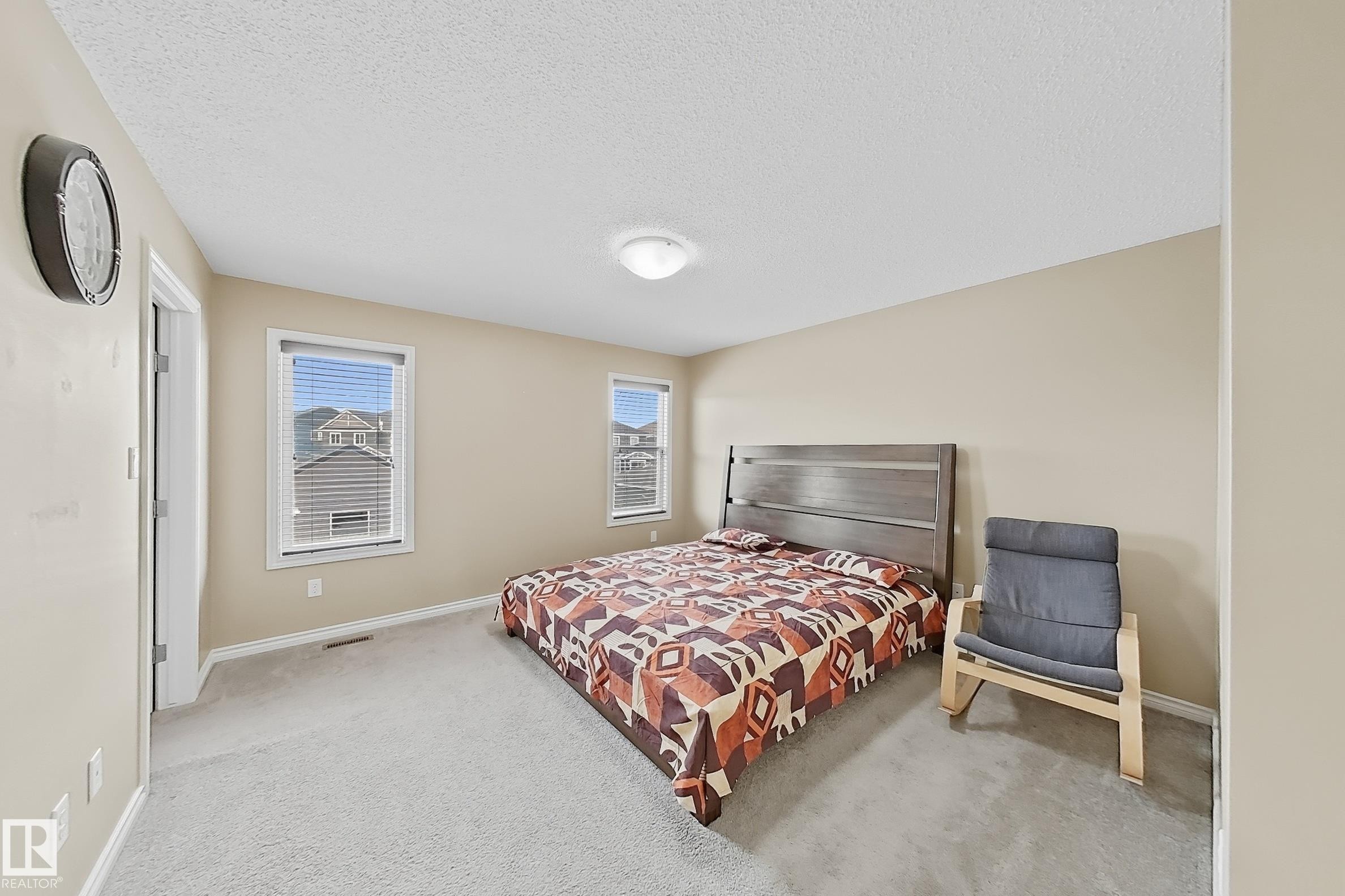 Carpeted room featuring neutral-toned walls, two windows with blinds, a four lights fixture, and white trim - 3609 Weidle Bend, Edmonton, AB - Indoor Photo Showing Bedroom