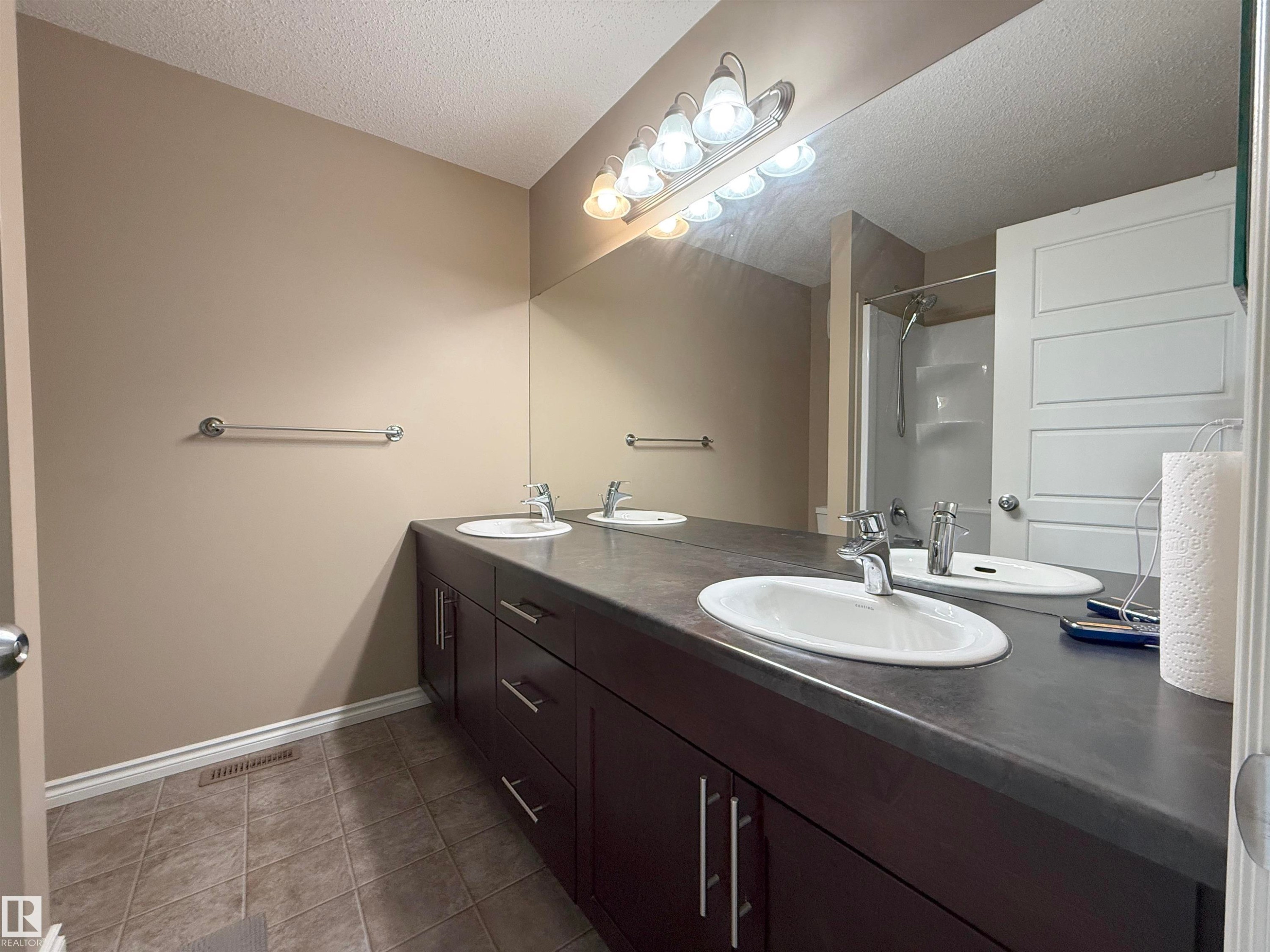 Double vanity with dark wood-finish cabinetry, dual undermount sinks, and a full-width mirror - 3609 Weidle Bend, Edmonton, AB - Indoor Photo Showing Bathroom