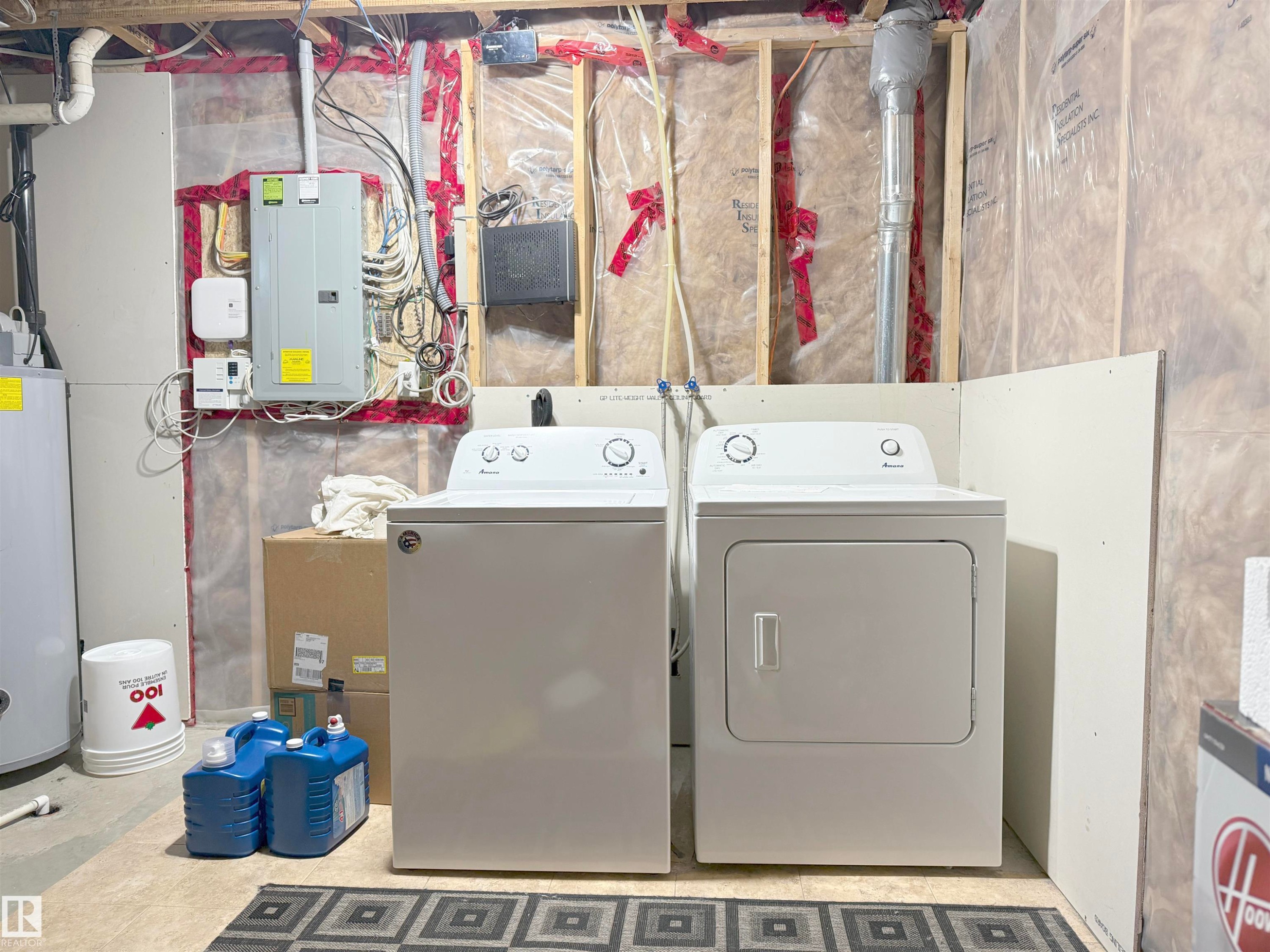 Utility area featuring a top-load washing machine, front-load dryer, exposed wall studs, thermal insulation, and an electrical service panel - 3609 Weidle Bend, Edmonton, AB - Indoor Photo Showing Laundry Room