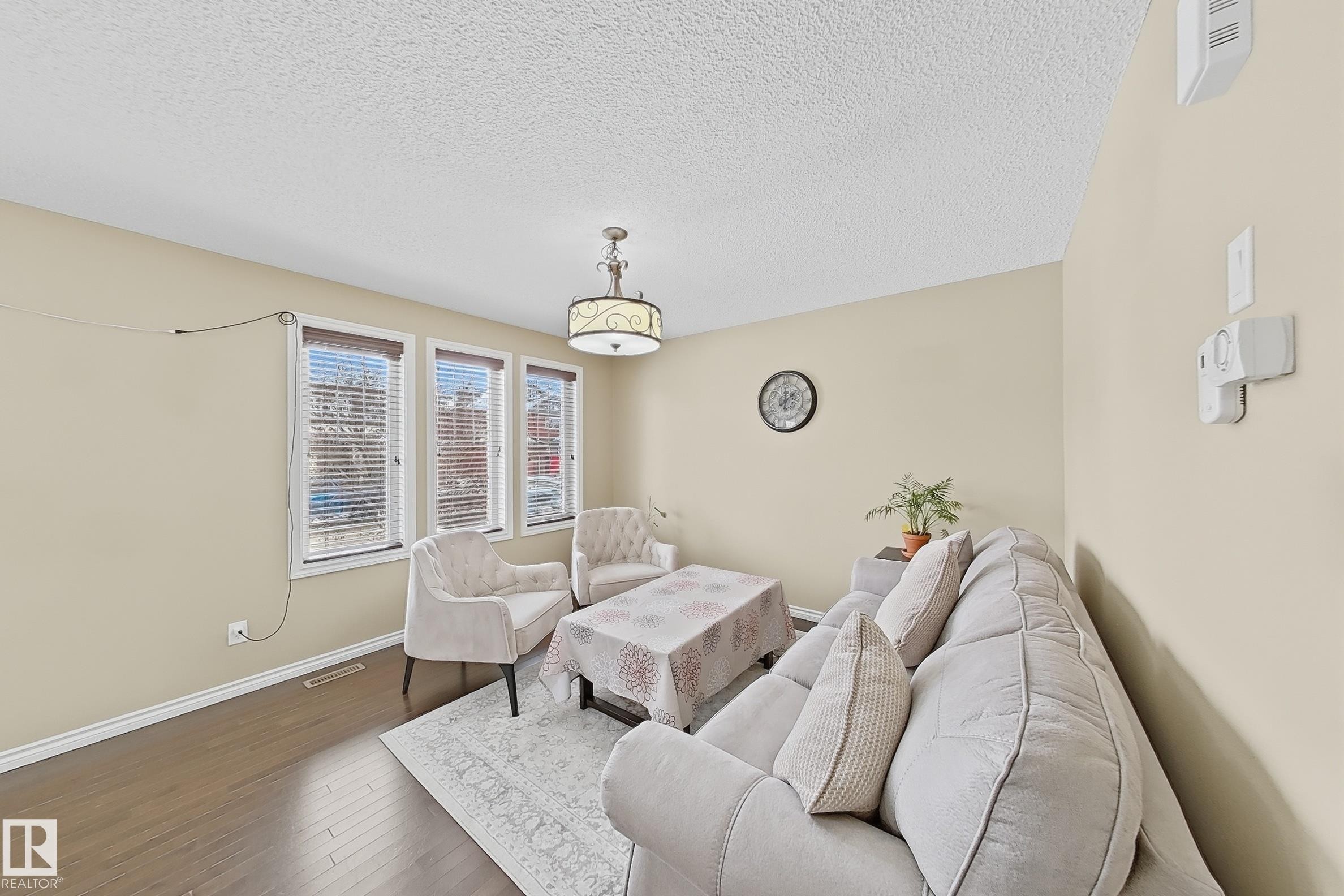 Living area with wood-finish flooring, light neutral-toned walls, and a textured ceiling - 3609 Weidle Bend, Edmonton, AB - Indoor Photo Showing Living Room