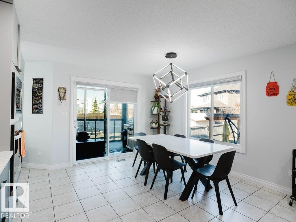 Bright dining area with white tile flooring and a modern geometric pendant light fixture - 5701 Rue Eaglemont, Beaumont, AB - Indoor Photo Showing Dining Room