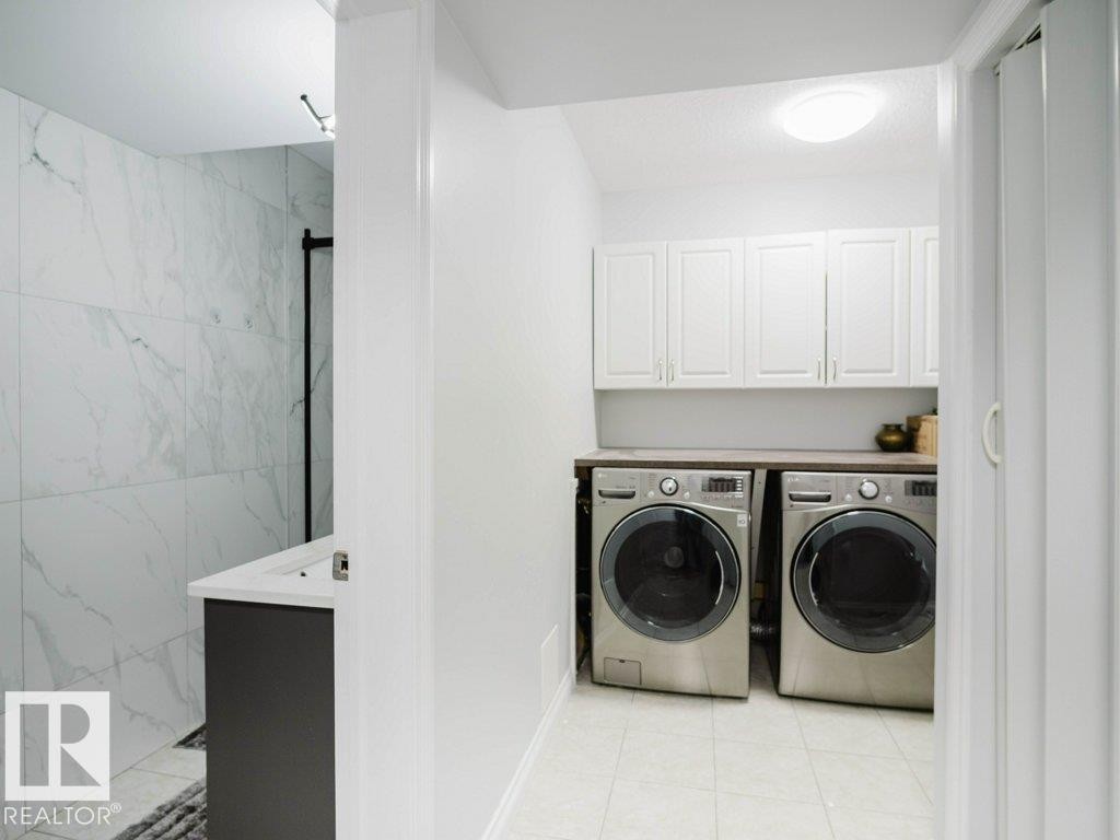 Dedicated laundry area featuring white upper cabinetry and a dark countertop - 5701 Rue Eaglemont, Beaumont, AB - Indoor Photo Showing Laundry Room