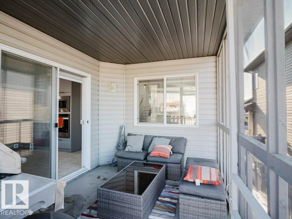 Screened-in porch featuring a dark gray slatted ceiling, light-colored horizontal siding, and a concrete floor - 5701 Rue Eaglemont, Beaumont, AB - Outdoor With Deck Patio Veranda With Exterior