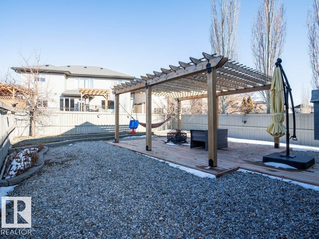 Expansive backyard featuring a large gravel area, a wood deck with a pergola, and a privacy fence - 5701 Rue Eaglemont, Beaumont, AB - Outdoor