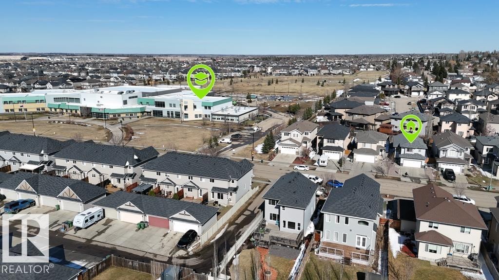 Residential neighborhood with varied architectural styles and a large institutional building visible in the background - 5701 Rue Eaglemont, Beaumont, AB - Outdoor With View