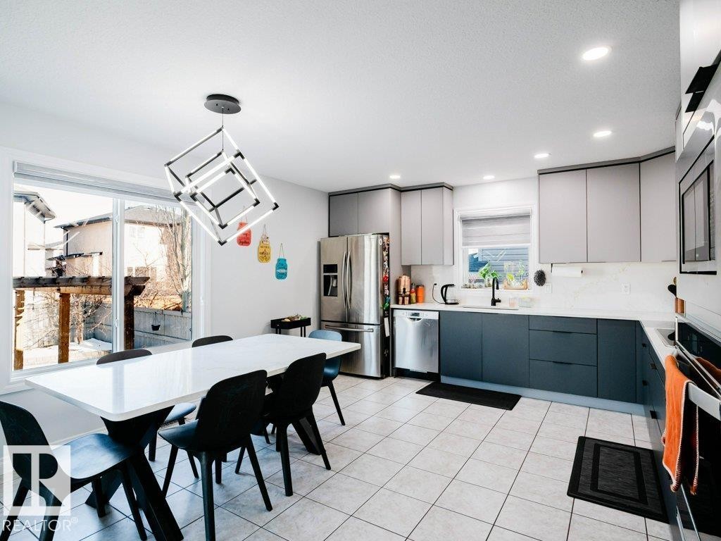 Modern kitchen featuring two-tone cabinetry, stainless steel appliances, and a tiled floor - 5701 Rue Eaglemont, Beaumont, AB - Indoor