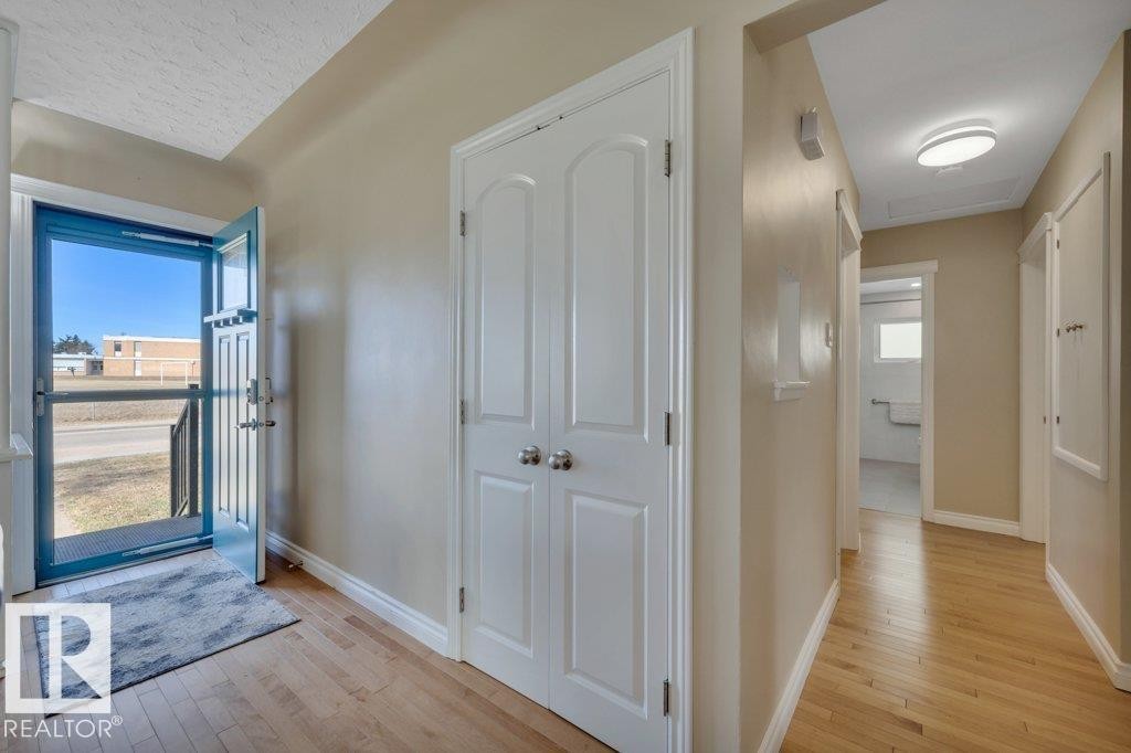 Entryway featuring natural wood-finish flooring, light beige wall paint, white trim, and a white double bifold closet - 10633 St Gabriel School Road, Edmonton, AB - Indoor Photo Showing Other Room