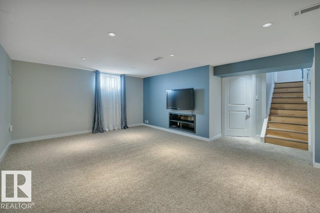 Spacious room featuring light-colored carpeting, recessed ceiling lighting, and a blue accent wall with a built-in media niche - 10633 St Gabriel School Road, Edmonton, AB - Indoor