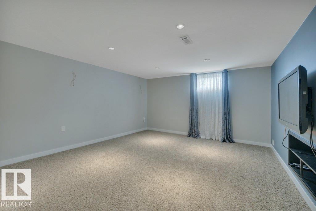 Spacious room featuring light-colored carpeting, recessed lighting, and a window with sheer and patterned drapes - 10633 St Gabriel School Road, Edmonton, AB - Indoor Photo Showing Other Room