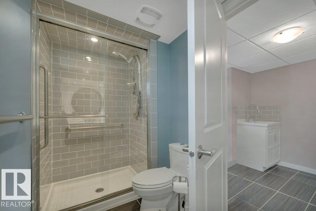 Full bathroom featuring a glass-enclosed shower with subway tile surround, white toilet, and tile flooring - 10633 St Gabriel School Road, Edmonton, AB - Indoor Photo Showing Bathroom