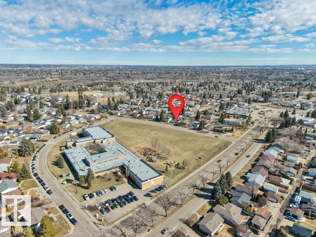 Residential area featuring individual homes, paved streets, and a large institutional building with a sports field - 10633 St Gabriel School Road, Edmonton, AB - Outdoor With View