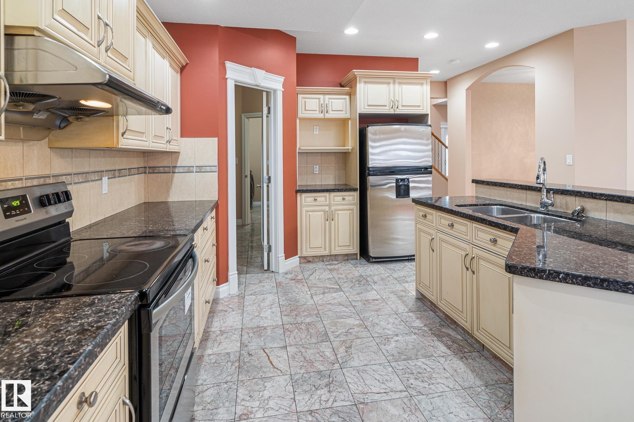 Kitchen featuring cream cabinetry, dark countertops, stainless steel appliances, and a tiled floor - 3455 29 Street, Edmonton, AB - Indoor Photo Showing Kitchen With Double Sink With Upgraded Kitchen