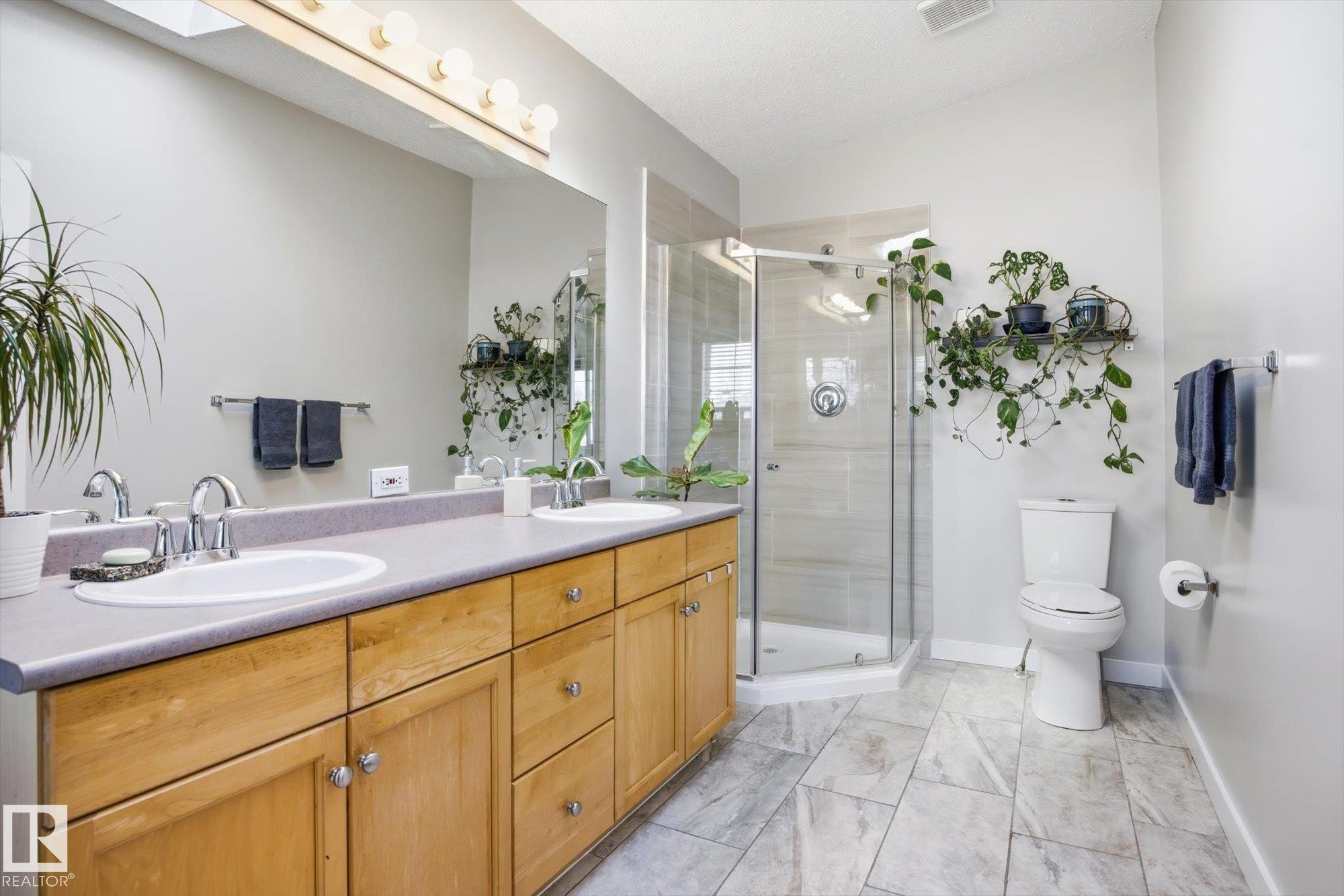 Bathroom featuring a dual-sink vanity with light wood cabinetry, a glass-enclosed shower, a wall-mounted vanity mirror, and recessed lighting - 2251 Brennan Court, Edmonton, AB - Indoor Photo Showing Bathroom