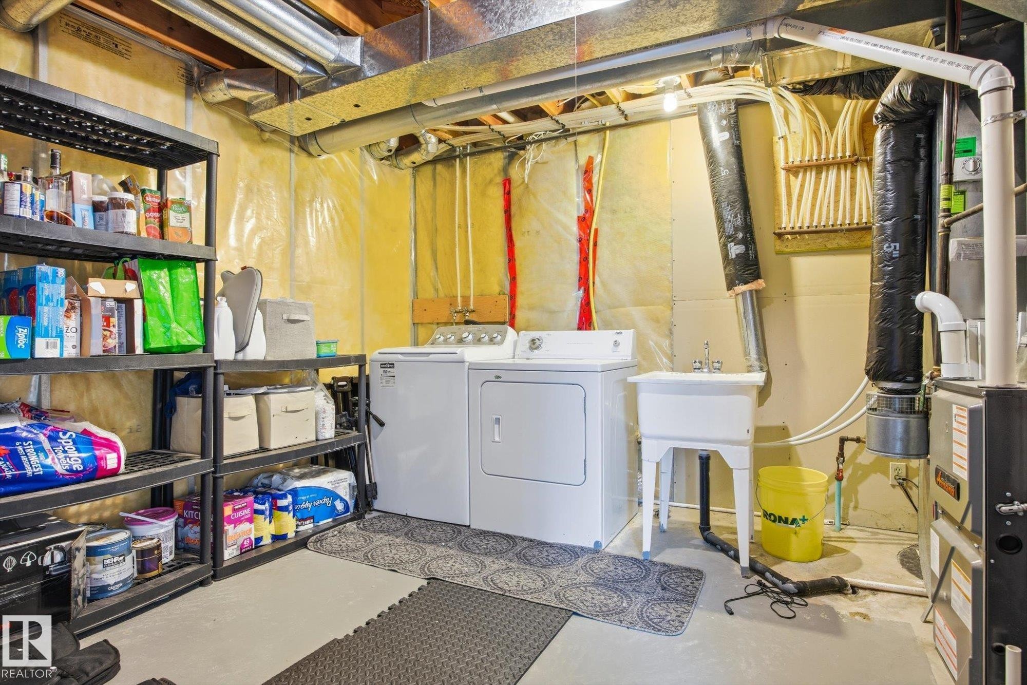 Dedicated utility area featuring a washer and dryer, laundry sink, and existing shelving - 2251 Brennan Court, Edmonton, AB - Indoor