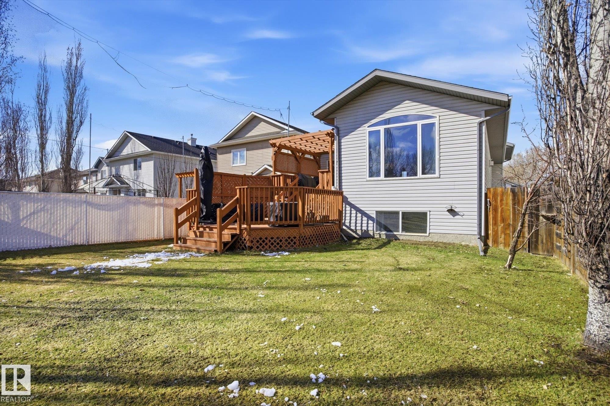 Expansive backyard featuring a manicured lawn, a two-tier wood deck with a pergola, a partial wood privacy fence, and a partial chain-link fence - 2251 Brennan Court, Edmonton, AB - Outdoor