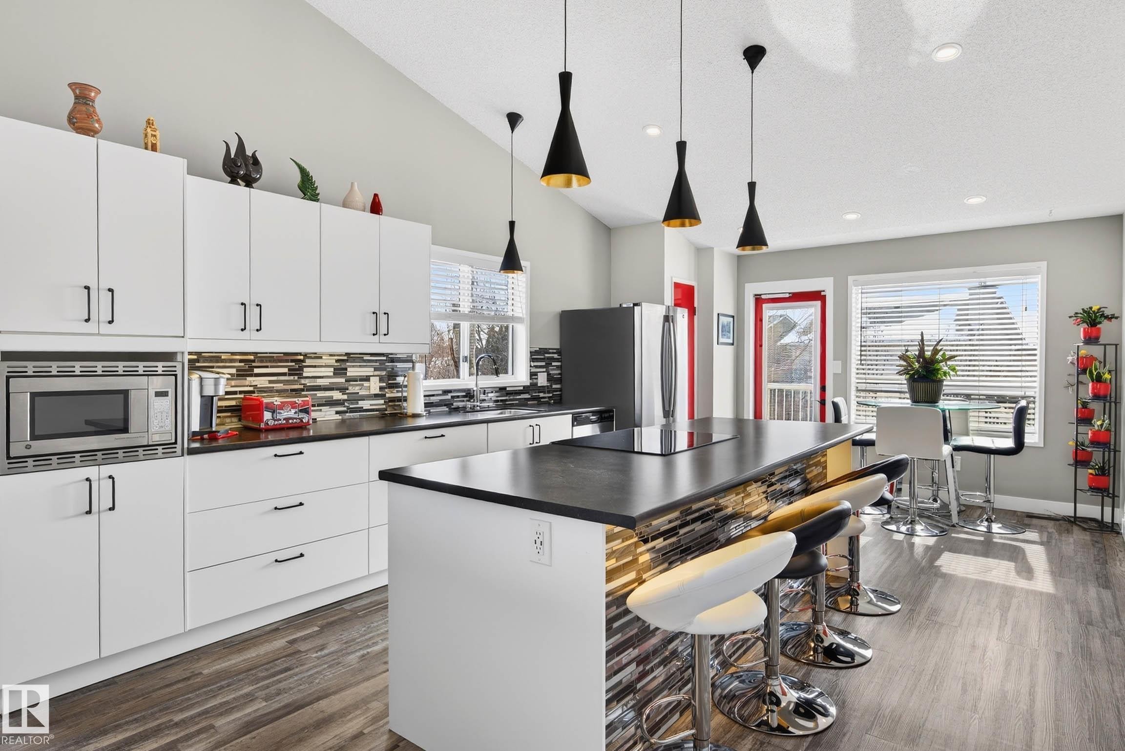 The kitchen features white cabinetry, a built-in microwave, and a large island with a cooktop and seating - 34 Donald Place, St. Albert, AB - Indoor Photo Showing Kitchen With Upgraded Kitchen